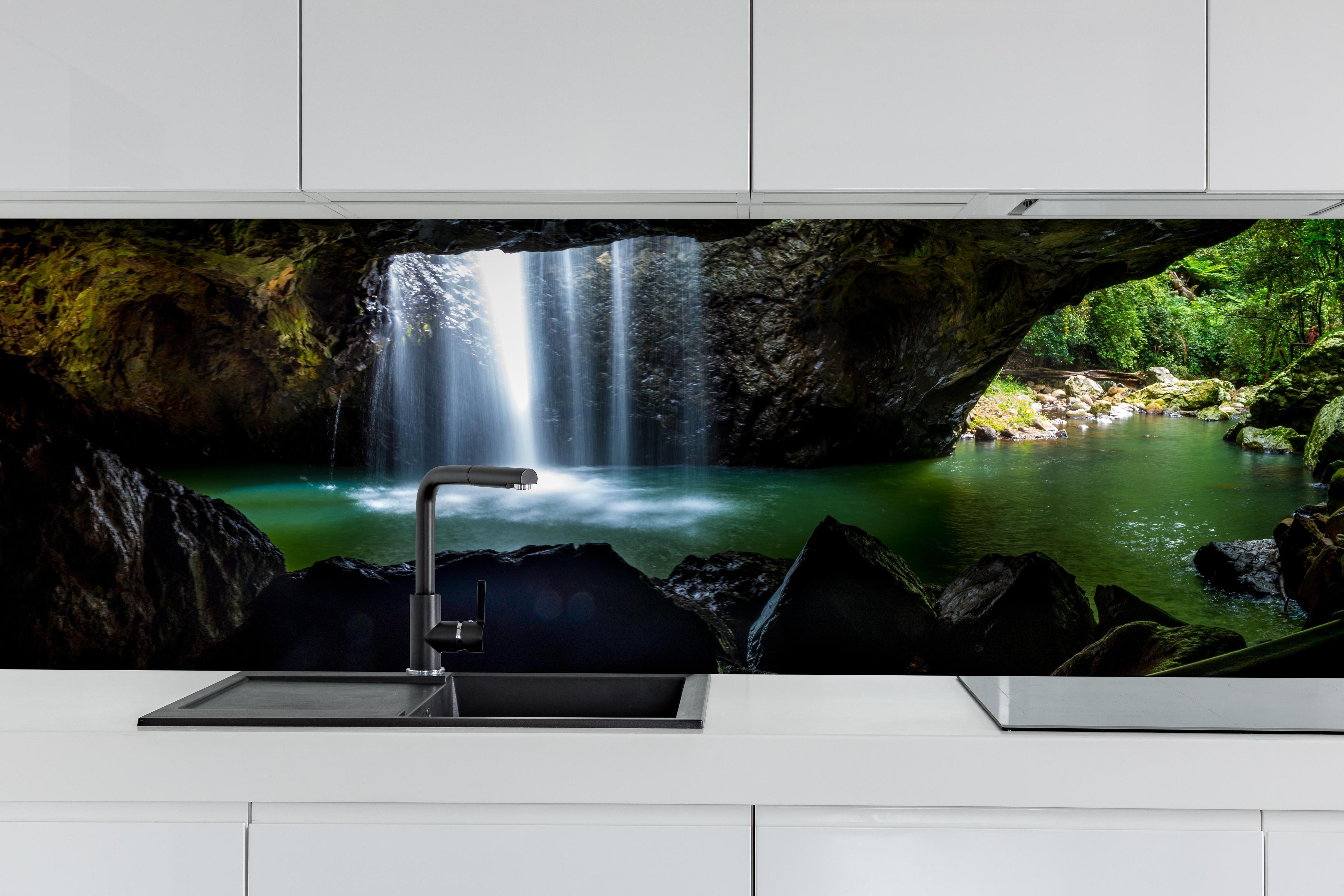 Küche - Wasserfall in der Höhle hinter weißen Hochglanz-Küchenregalen und schwarzem Wasserhahn