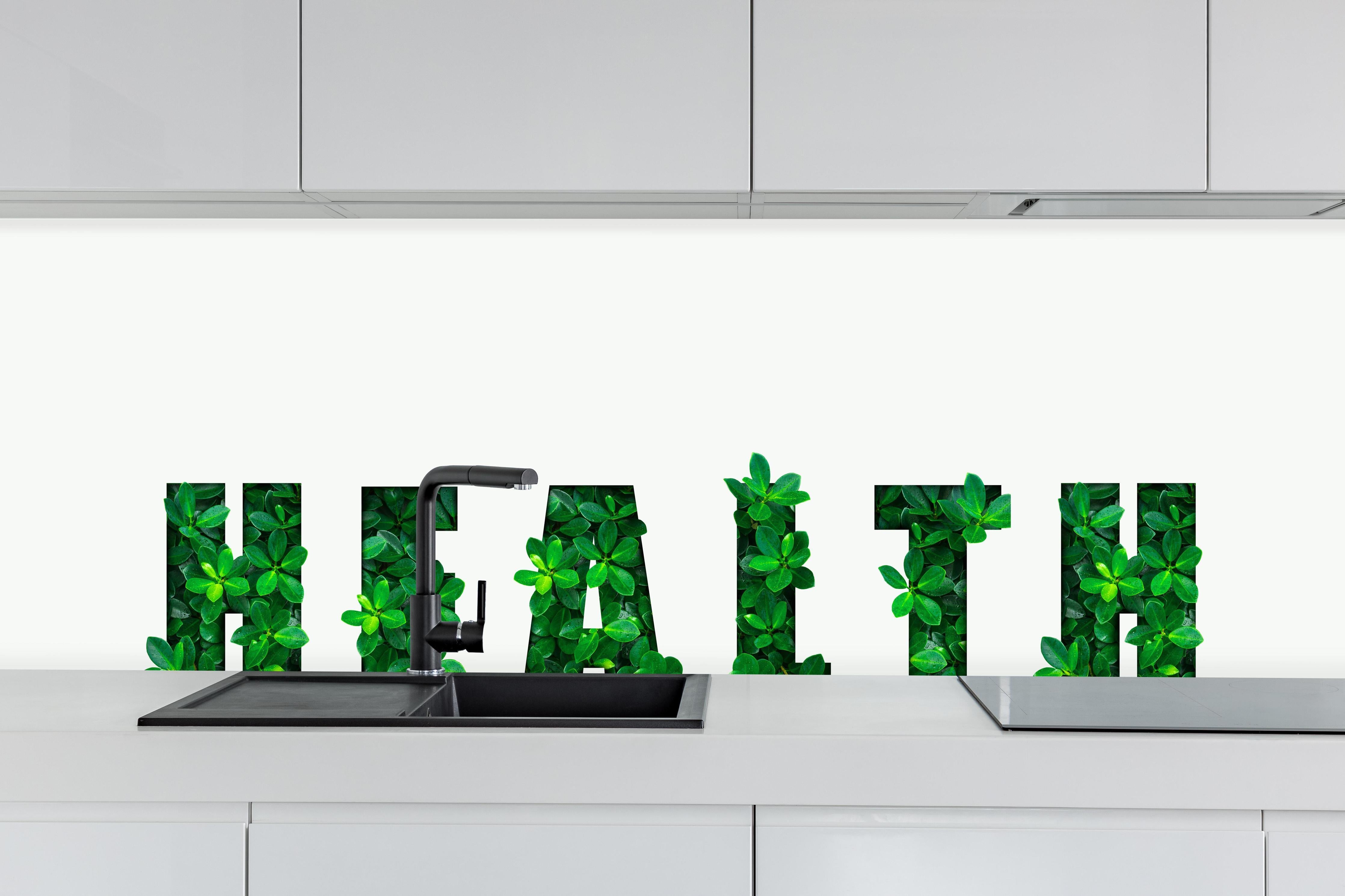 Küche - Wort HEALTH aus grünen Blättern hinter weißen Hochglanz-Küchenregalen und schwarzem Wasserhahn