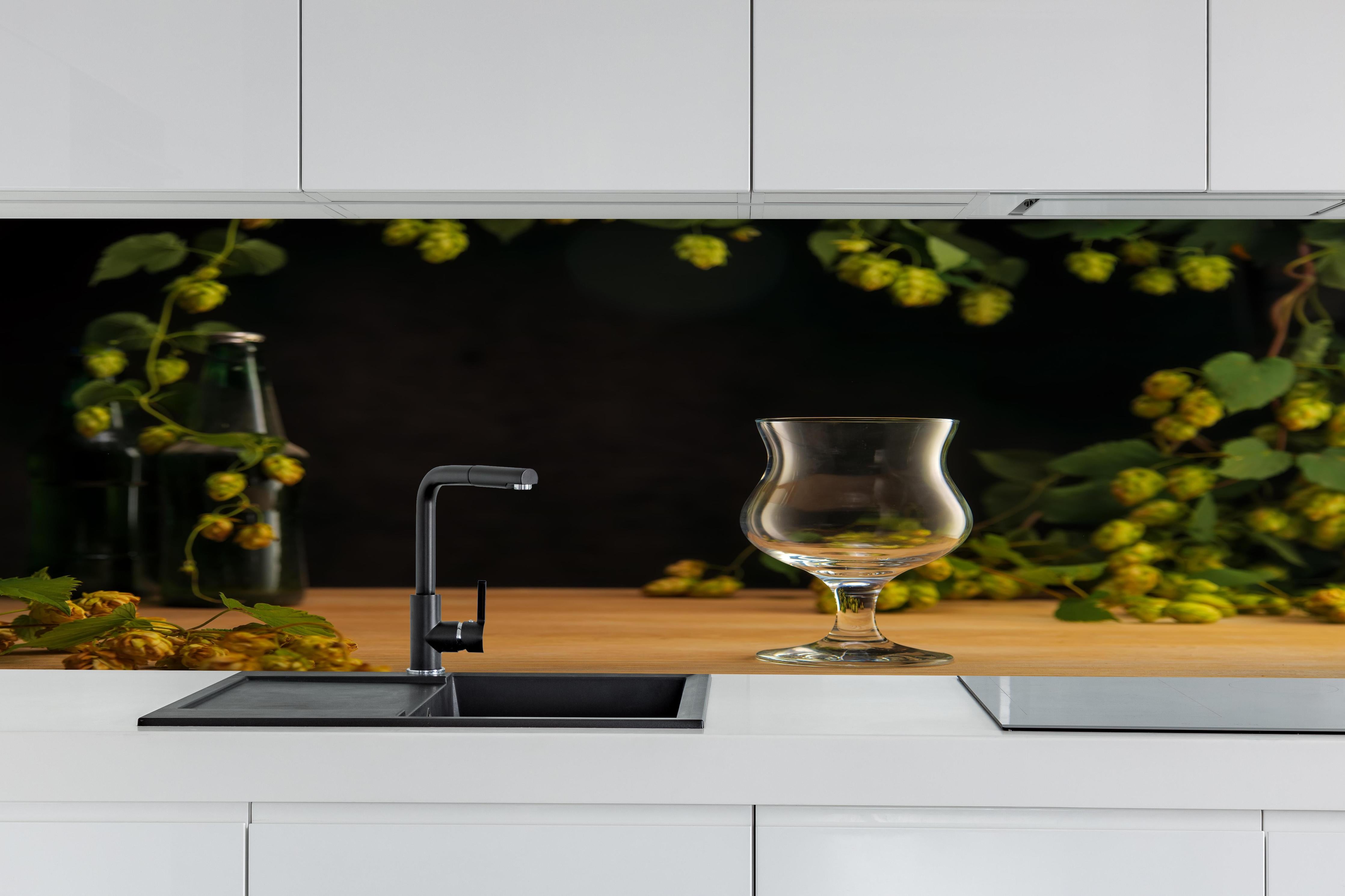 Küche - Leeres Tulpenglas auf Holztisch hinter weißen Hochglanz-Küchenregalen und schwarzem Wasserhahn