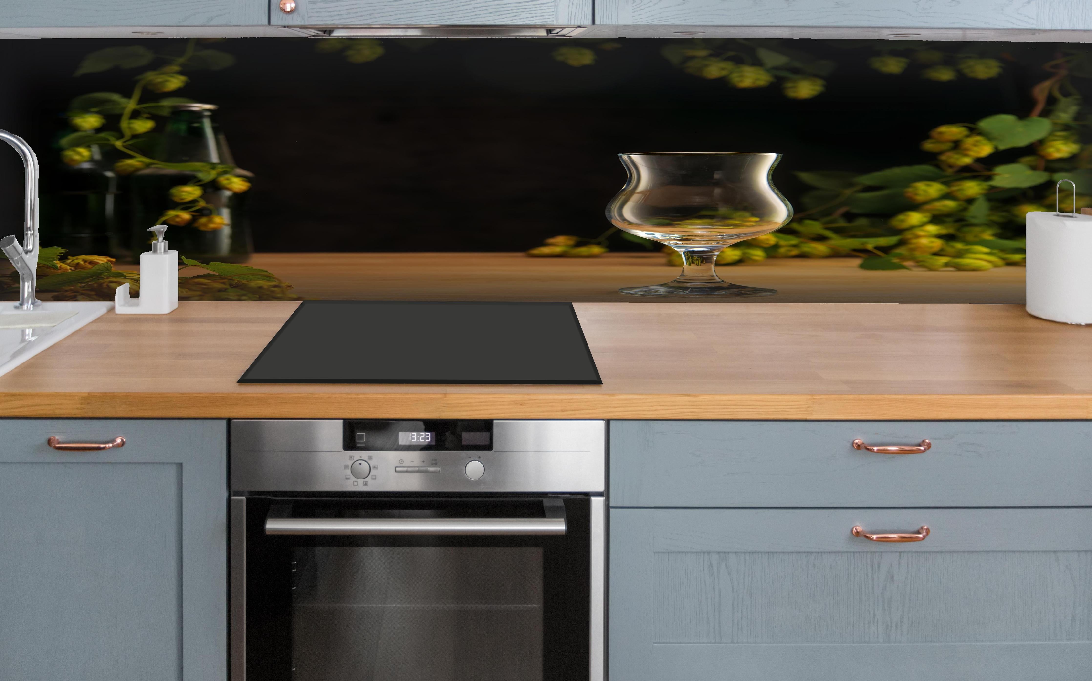 Küche - Leeres Tulpenglas auf Holztisch hinter weißen Hochglanz-Küchenregalen und schwarzem Wasserhahn