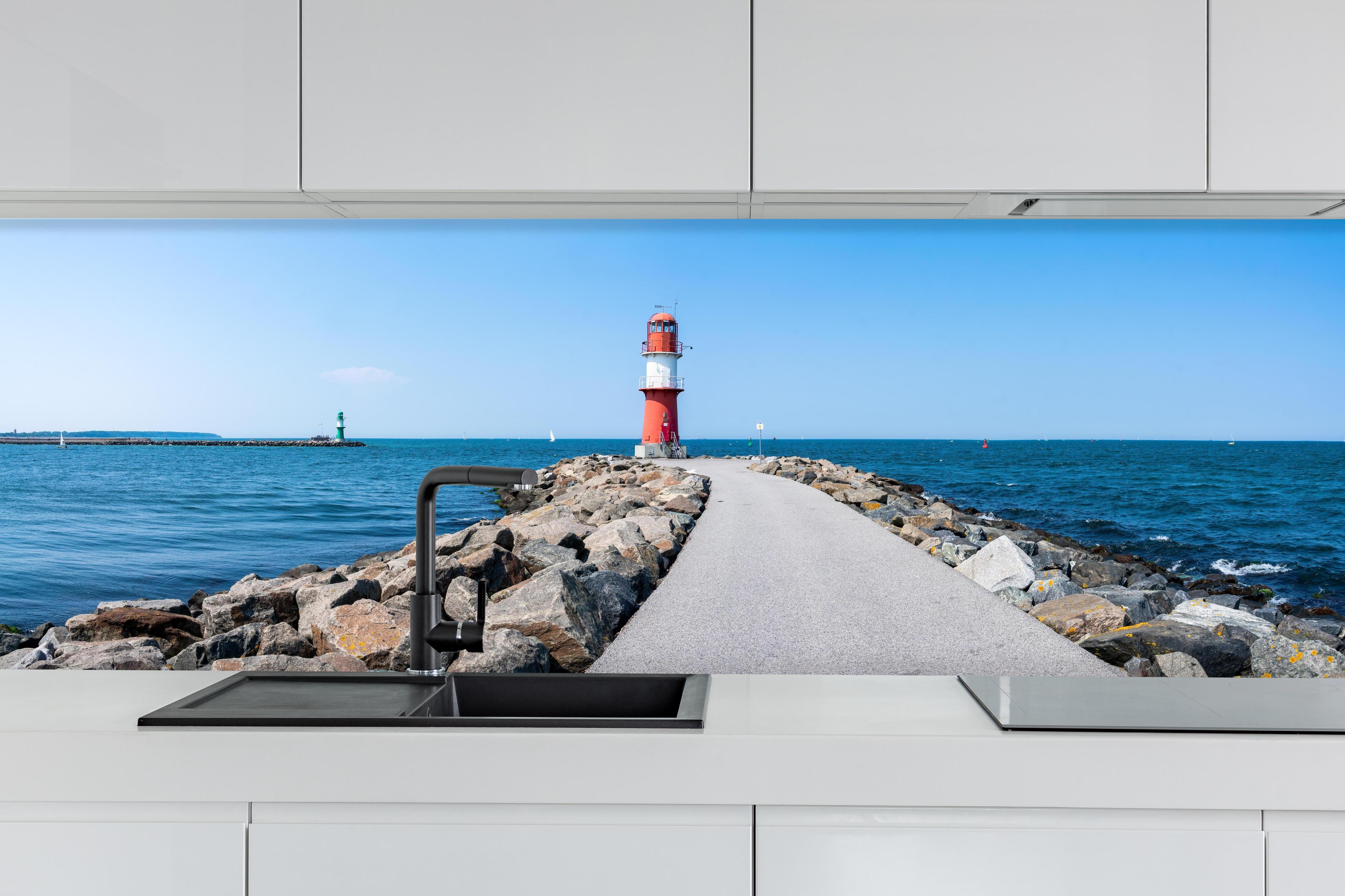 Küche - Leuchtturm an der Küste mit blauer See und klarem Himmel hinter weißen Hochglanz-Küchenregalen und schwarzem Wasserhahn