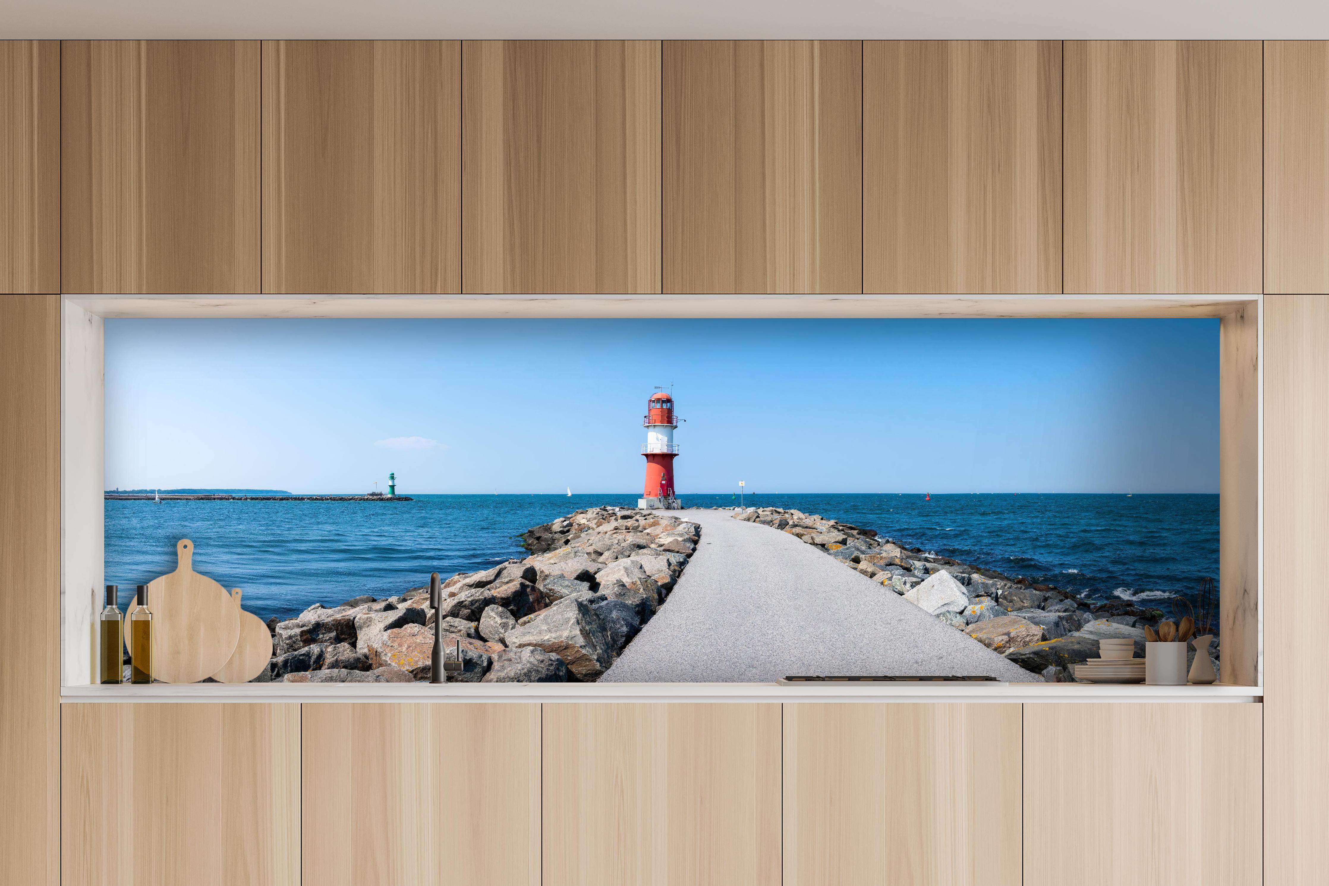 Küche - Leuchtturm an der Küste mit blauer See und klarem Himmel hinter weißen Hochglanz-Küchenregalen und schwarzem Wasserhahn