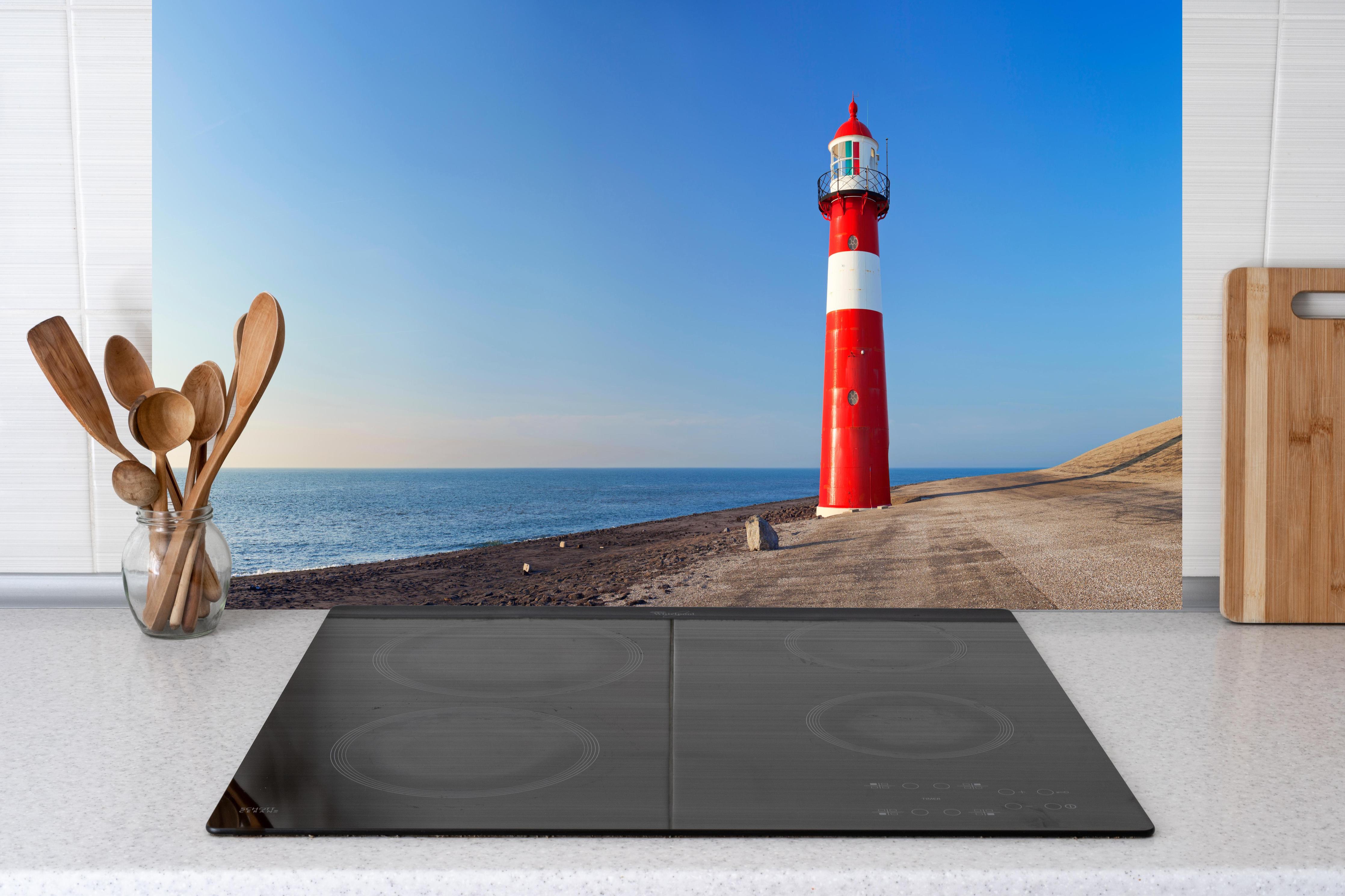 Küche - Leuchtturm in strahlendem Rot und Weiß vor weitem blauen Himmel hinter weißen Hochglanz-Küchenregalen und schwarzem Wasserhahn