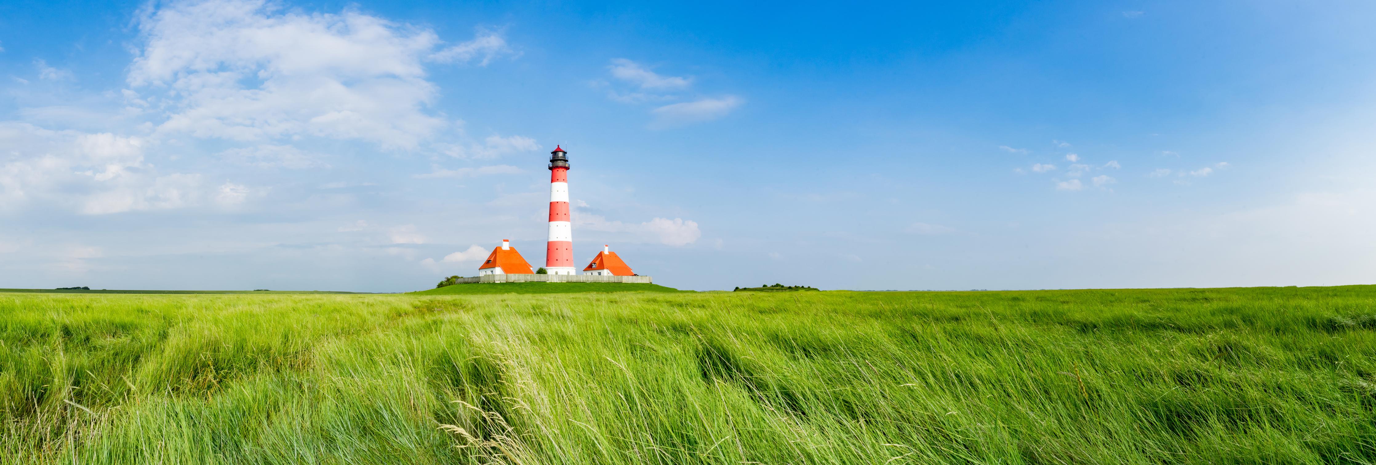 Küchenrückwand-Leuchtturm vor herrlicher grüner Wiese unter klarem Himmel