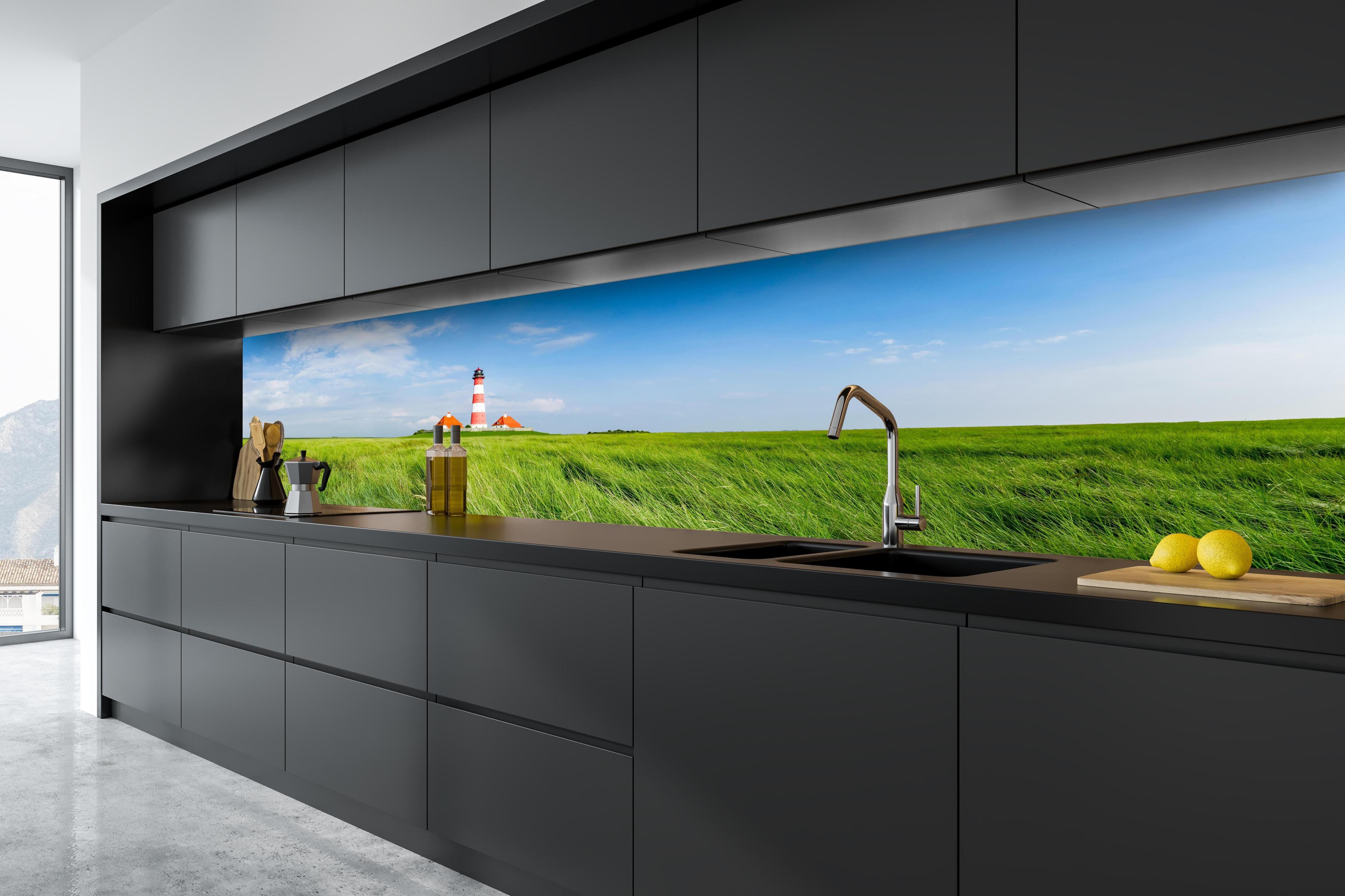 Küche - Leuchtturm vor herrlicher grüner Wiese unter klarem Himmel hinter weißen Hochglanz-Küchenregalen und schwarzem Wasserhahn