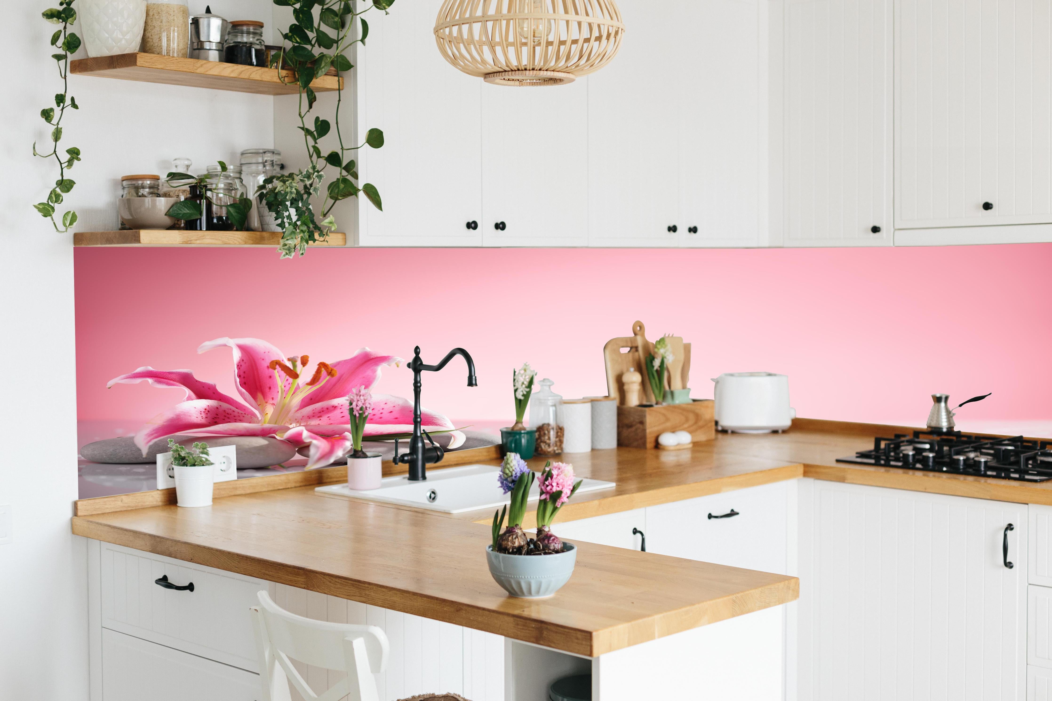 Küche - Lilie und Massagesteine hinter weißen Hochglanz-Küchenregalen und schwarzem Wasserhahn