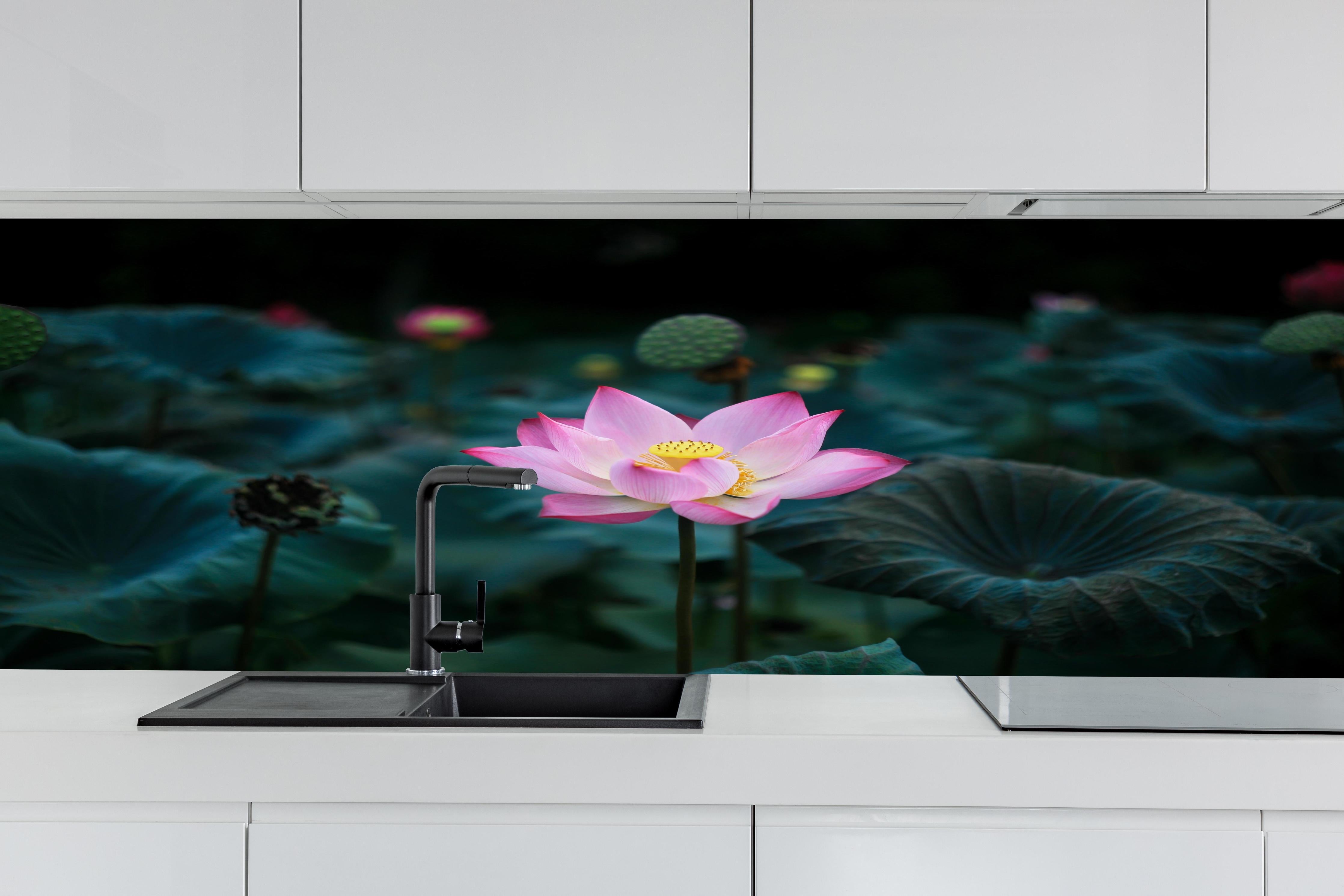 Küche - Lotosblume im Garten hinter weißen Hochglanz-Küchenregalen und schwarzem Wasserhahn