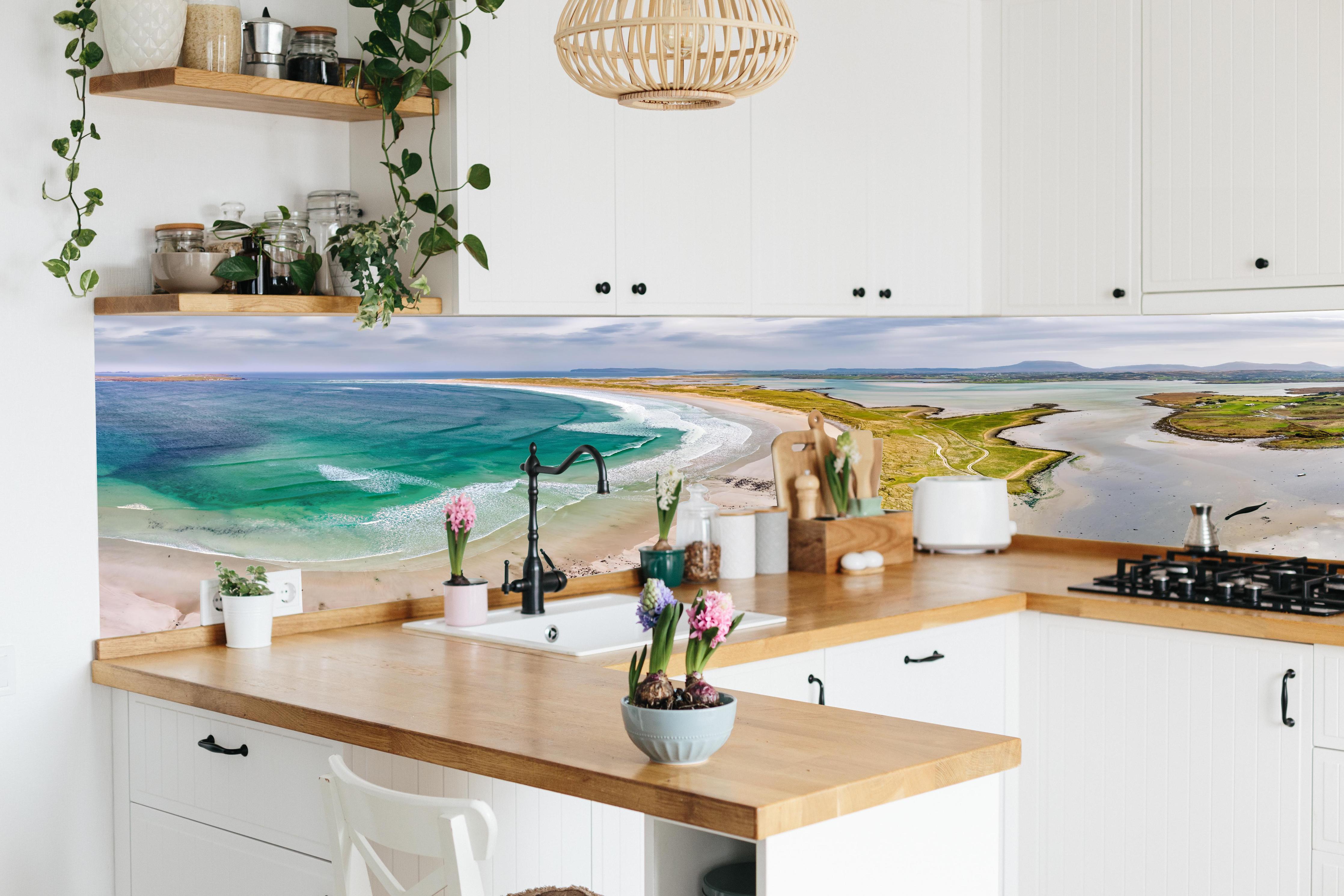 Küche - Luftaufnahme der Küste von Magheraroarty-Irland hinter weißen Hochglanz-Küchenregalen und schwarzem Wasserhahn