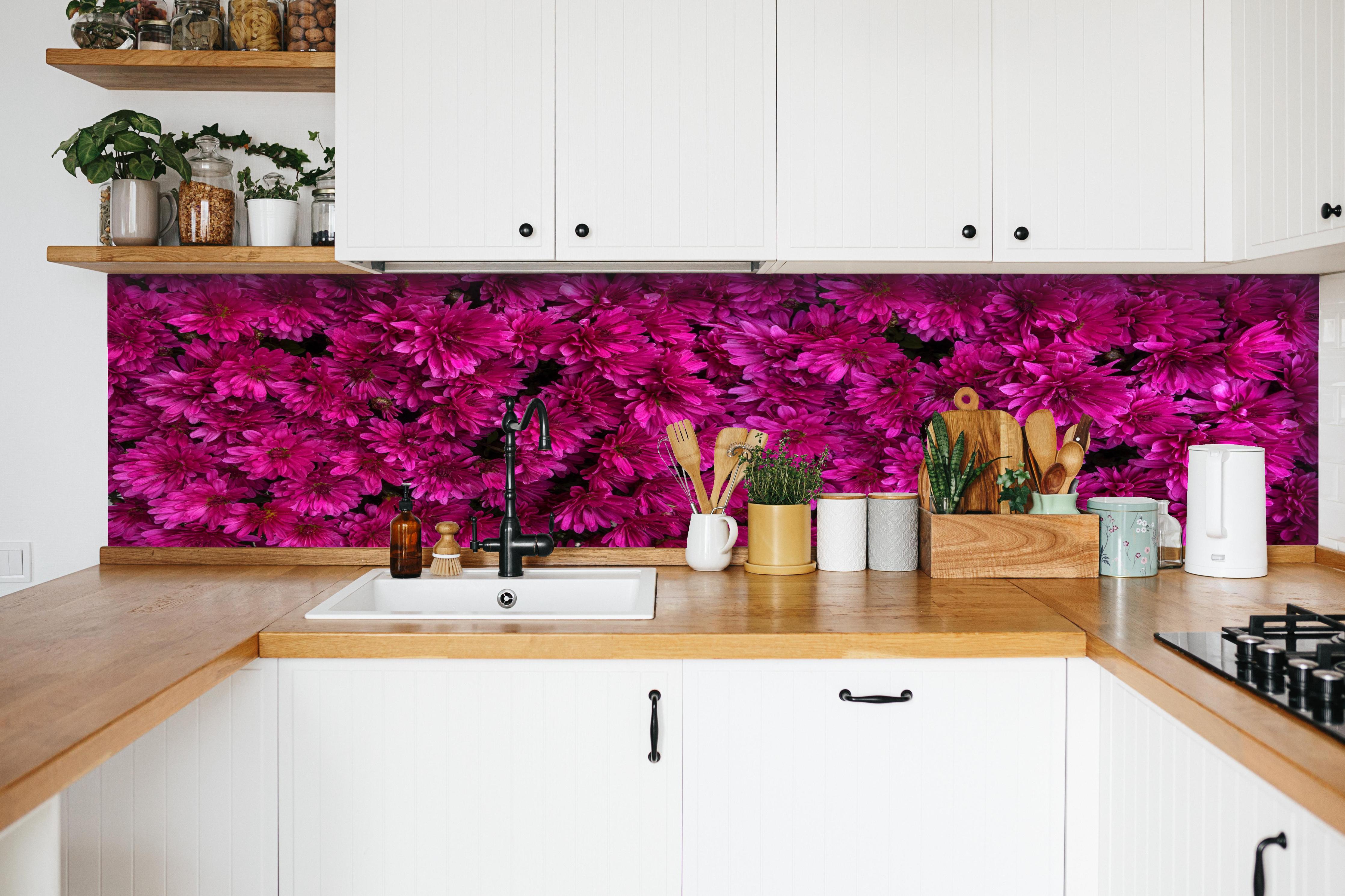 Küche - Magenta Blüten von Chrysanthemen hinter weißen Hochglanz-Küchenregalen und schwarzem Wasserhahn