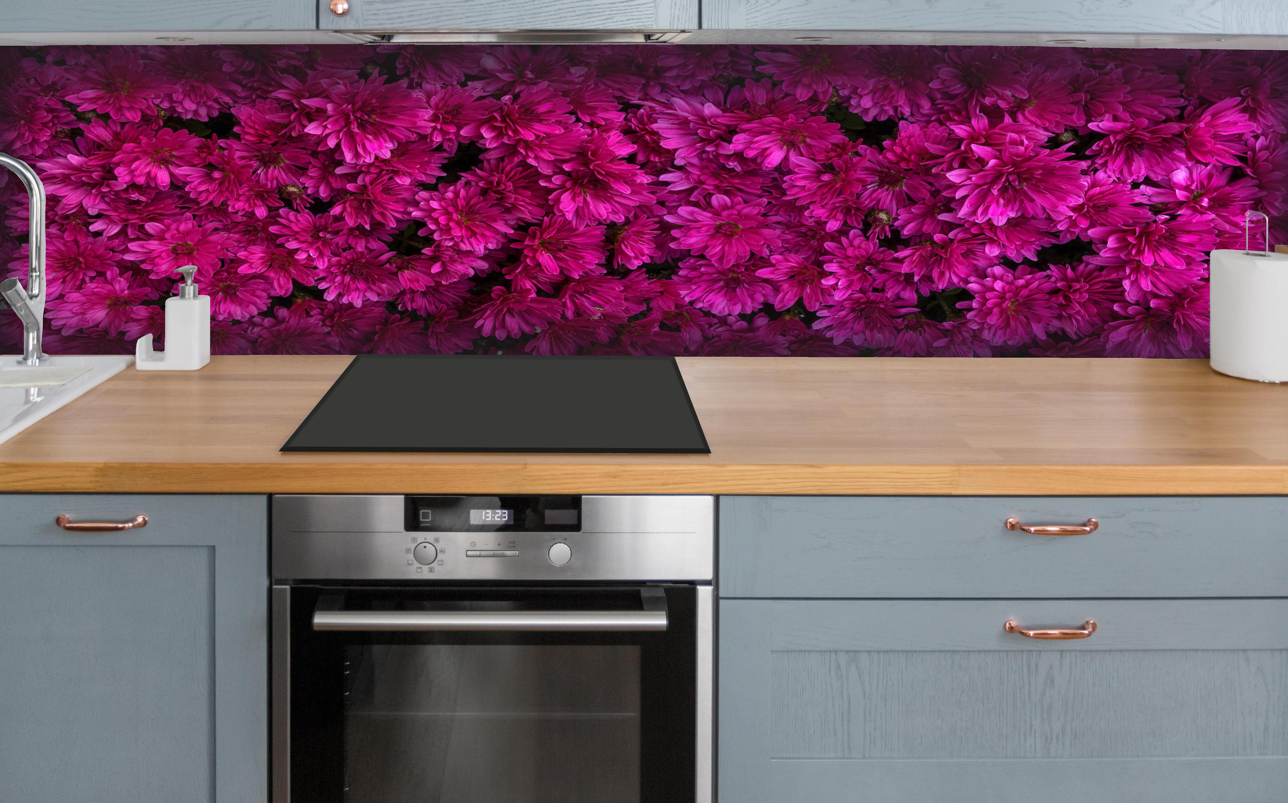 Küche - Magenta Blüten von Chrysanthemen hinter weißen Hochglanz-Küchenregalen und schwarzem Wasserhahn
