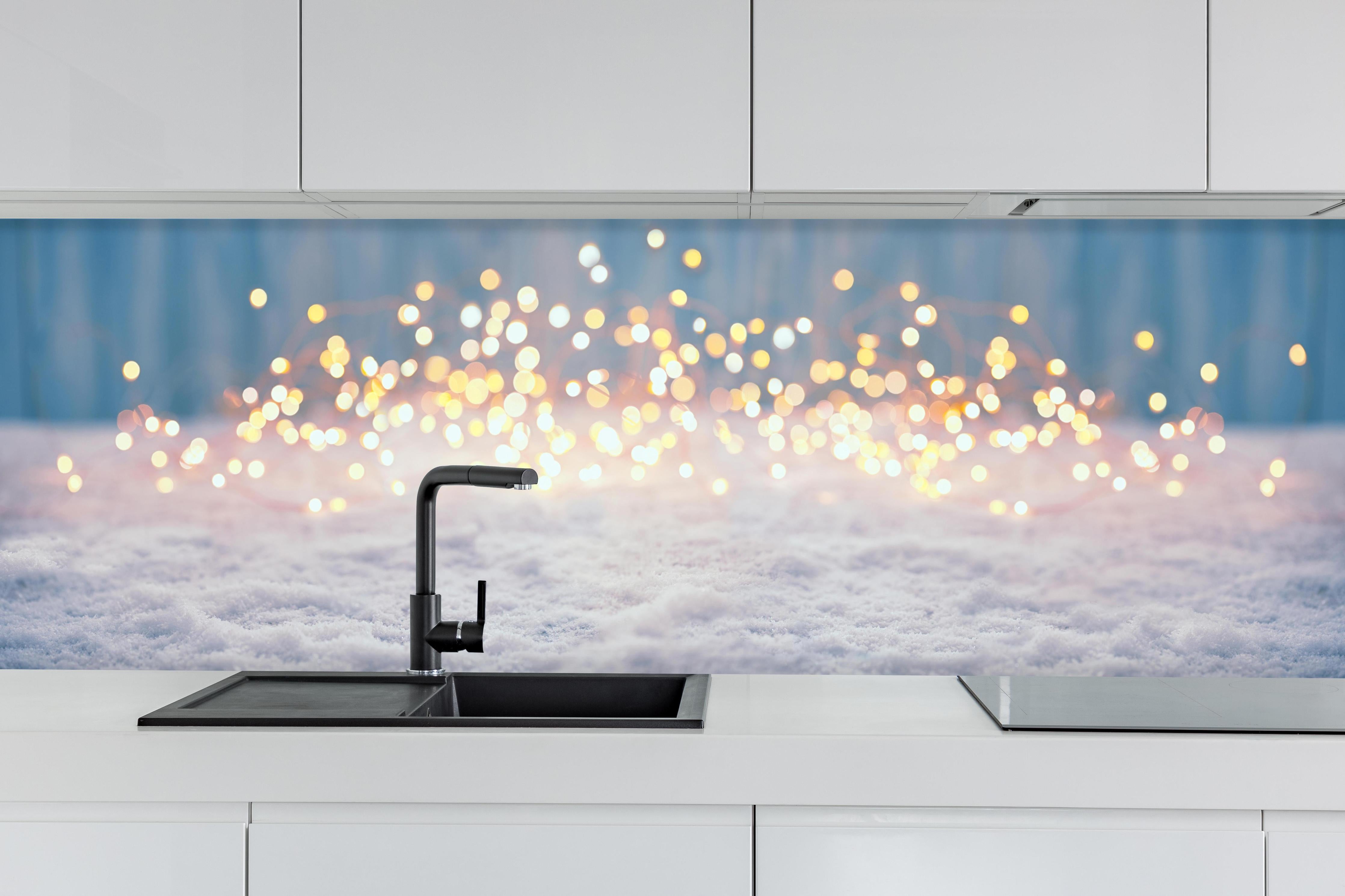 Küche - Magische Winterlandschaft mit goldenem Bokeh hinter weißen Hochglanz-Küchenregalen und schwarzem Wasserhahn