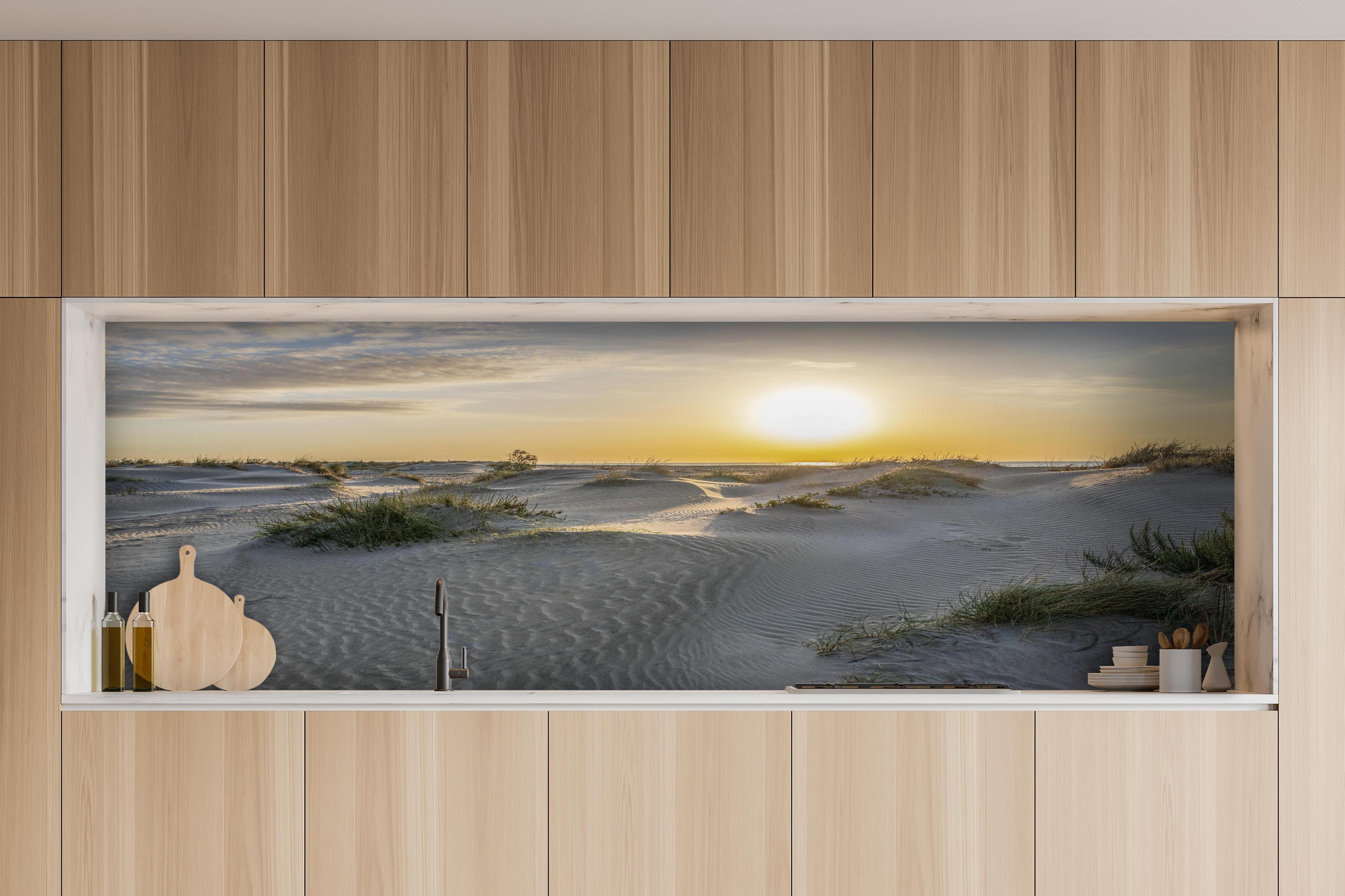 Küche - Malerische Sanddünenlandschaft mit goldenem Sonnenuntergang am Meer hinter weißen Hochglanz-Küchenregalen und schwarzem Wasserhahn