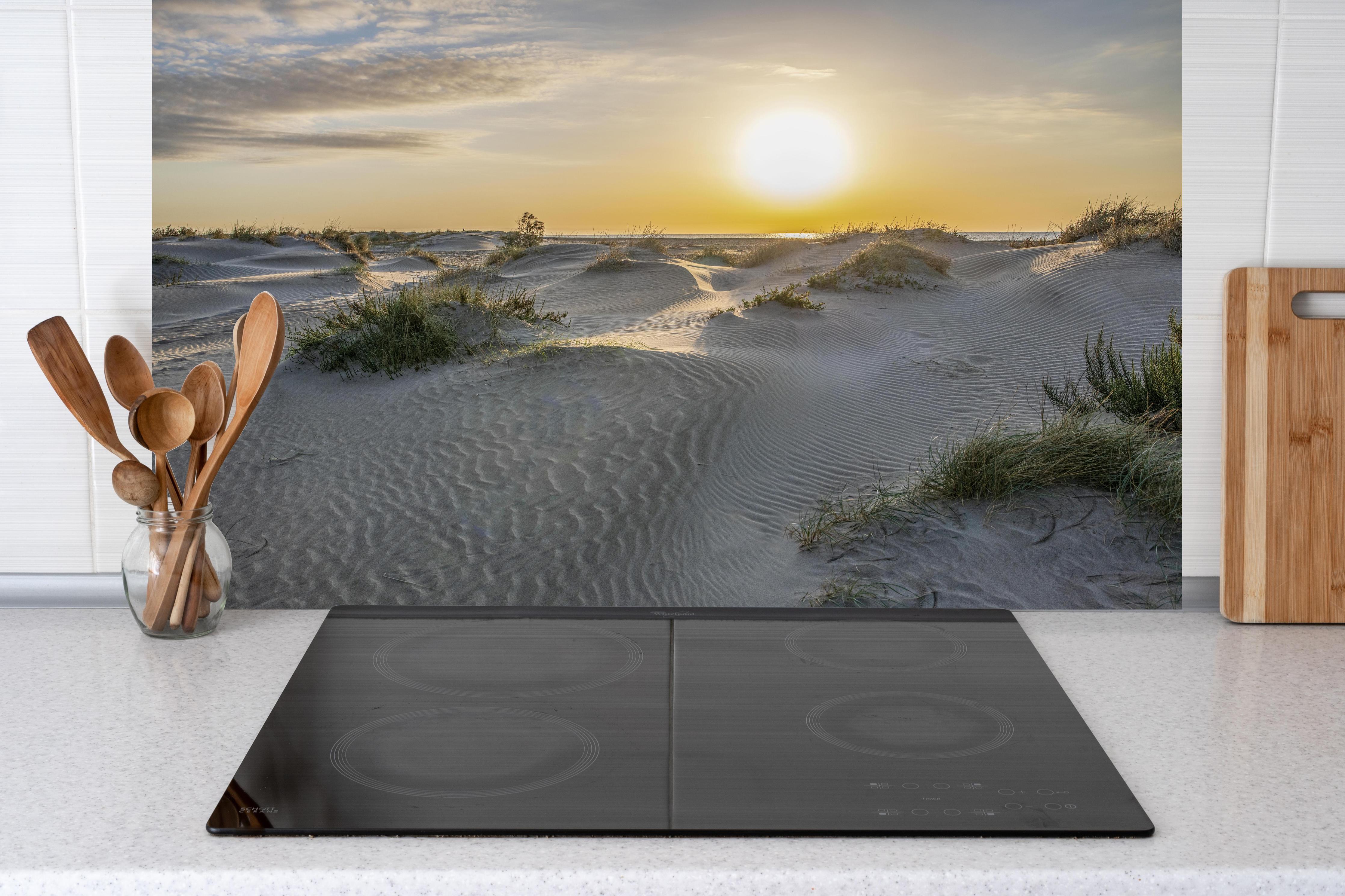 Küche - Malerische Sanddünenlandschaft mit goldenem Sonnenuntergang am Meer hinter weißen Hochglanz-Küchenregalen und schwarzem Wasserhahn
