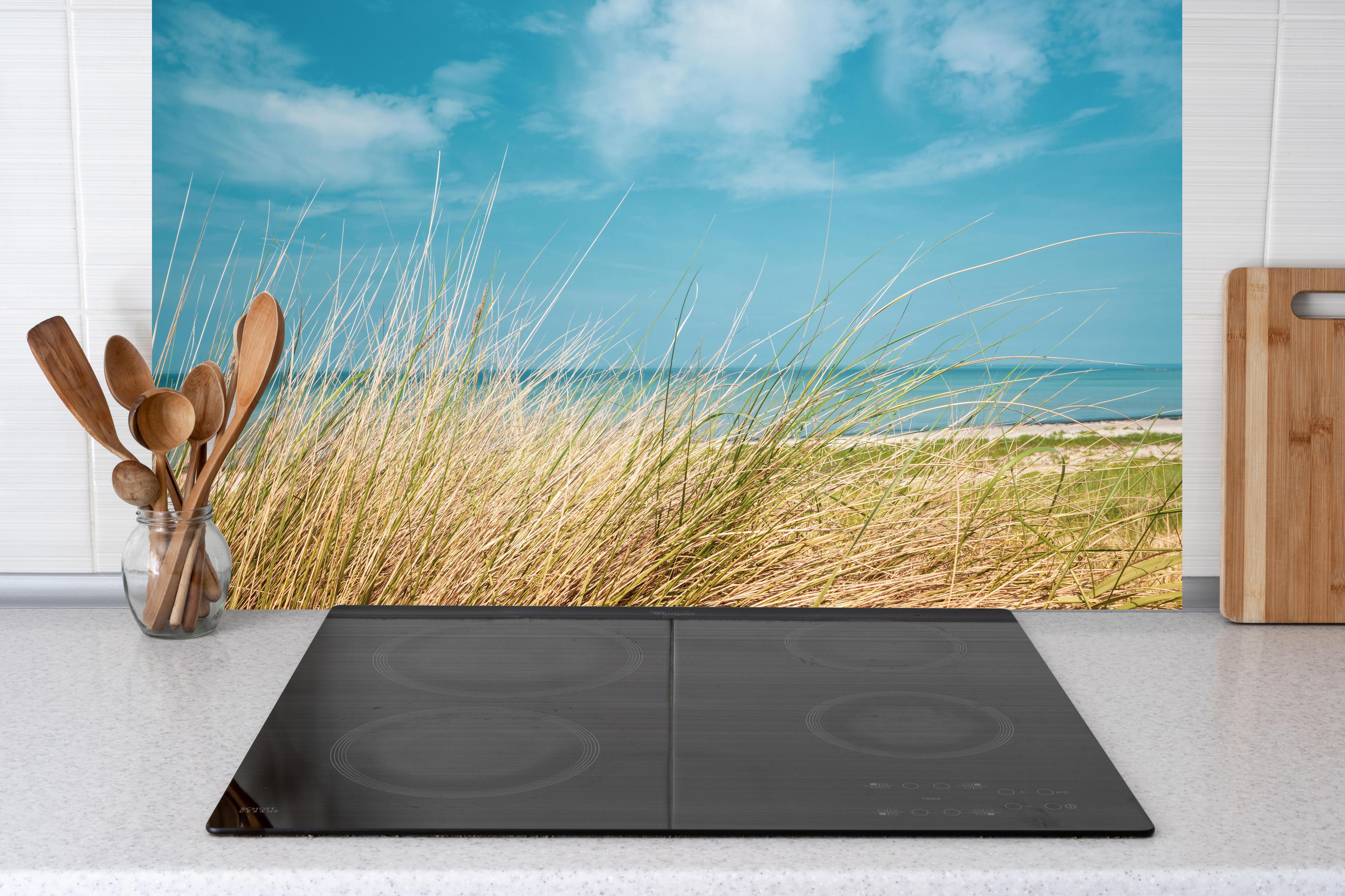 Küche - Malersicher Küstenabschnitt mit goldenem Gras und türkisem Himmel hinter weißen Hochglanz-Küchenregalen und schwarzem Wasserhahn