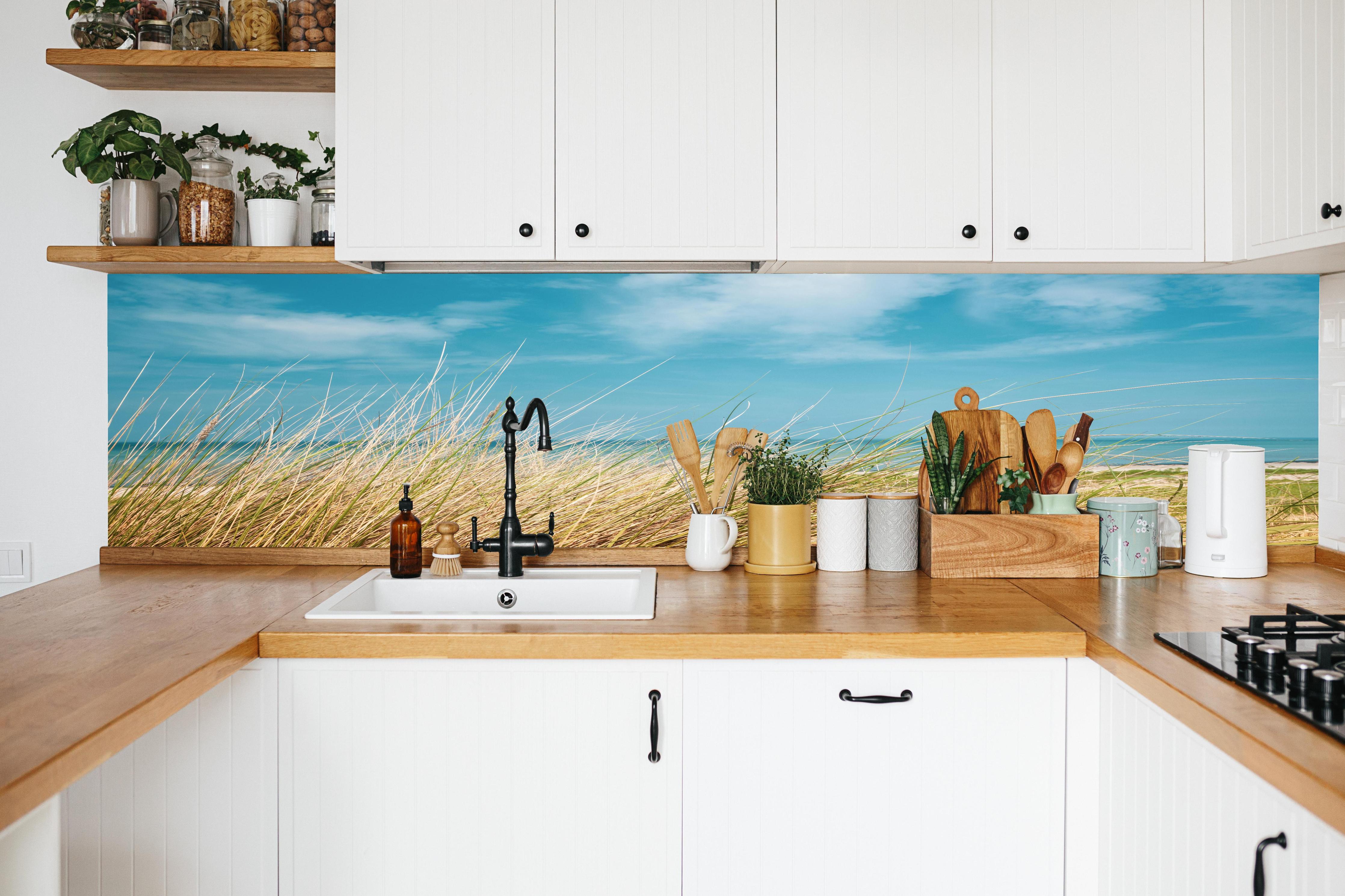Küche - Malersicher Küstenabschnitt mit goldenem Gras und türkisem Himmel hinter weißen Hochglanz-Küchenregalen und schwarzem Wasserhahn