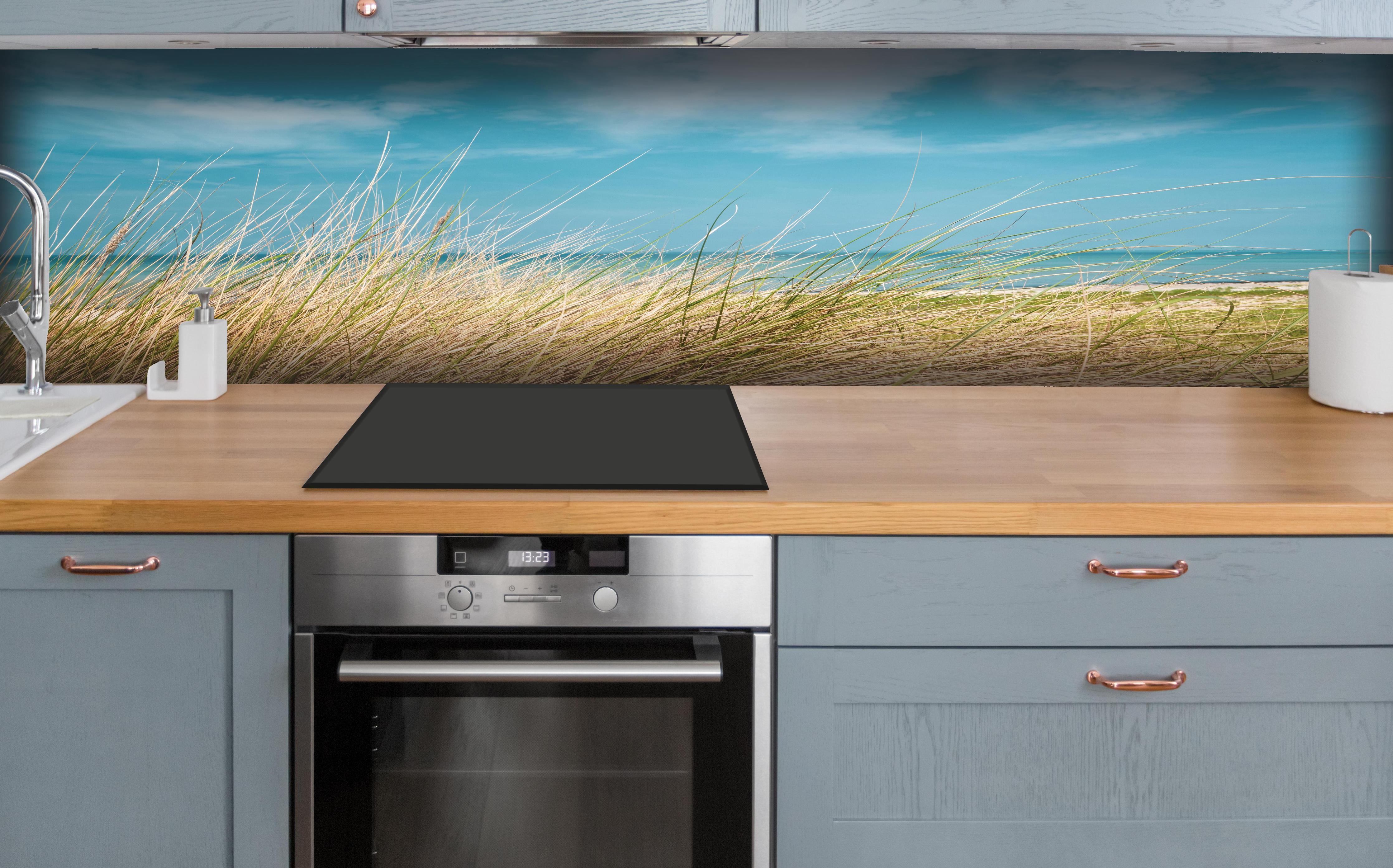 Küche - Malersicher Küstenabschnitt mit goldenem Gras und türkisem Himmel hinter weißen Hochglanz-Küchenregalen und schwarzem Wasserhahn