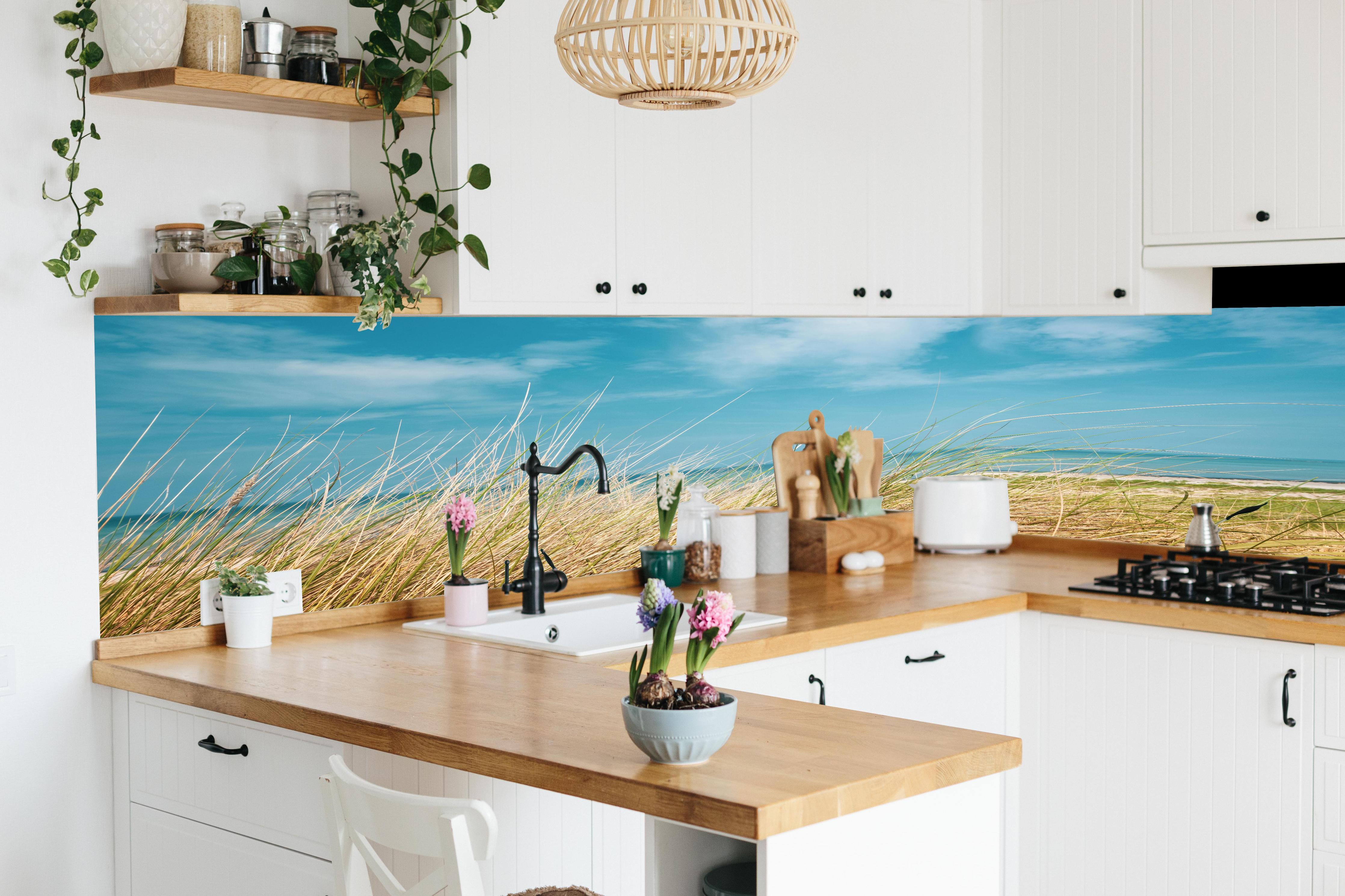 Küche - Malersicher Küstenabschnitt mit goldenem Gras und türkisem Himmel hinter weißen Hochglanz-Küchenregalen und schwarzem Wasserhahn