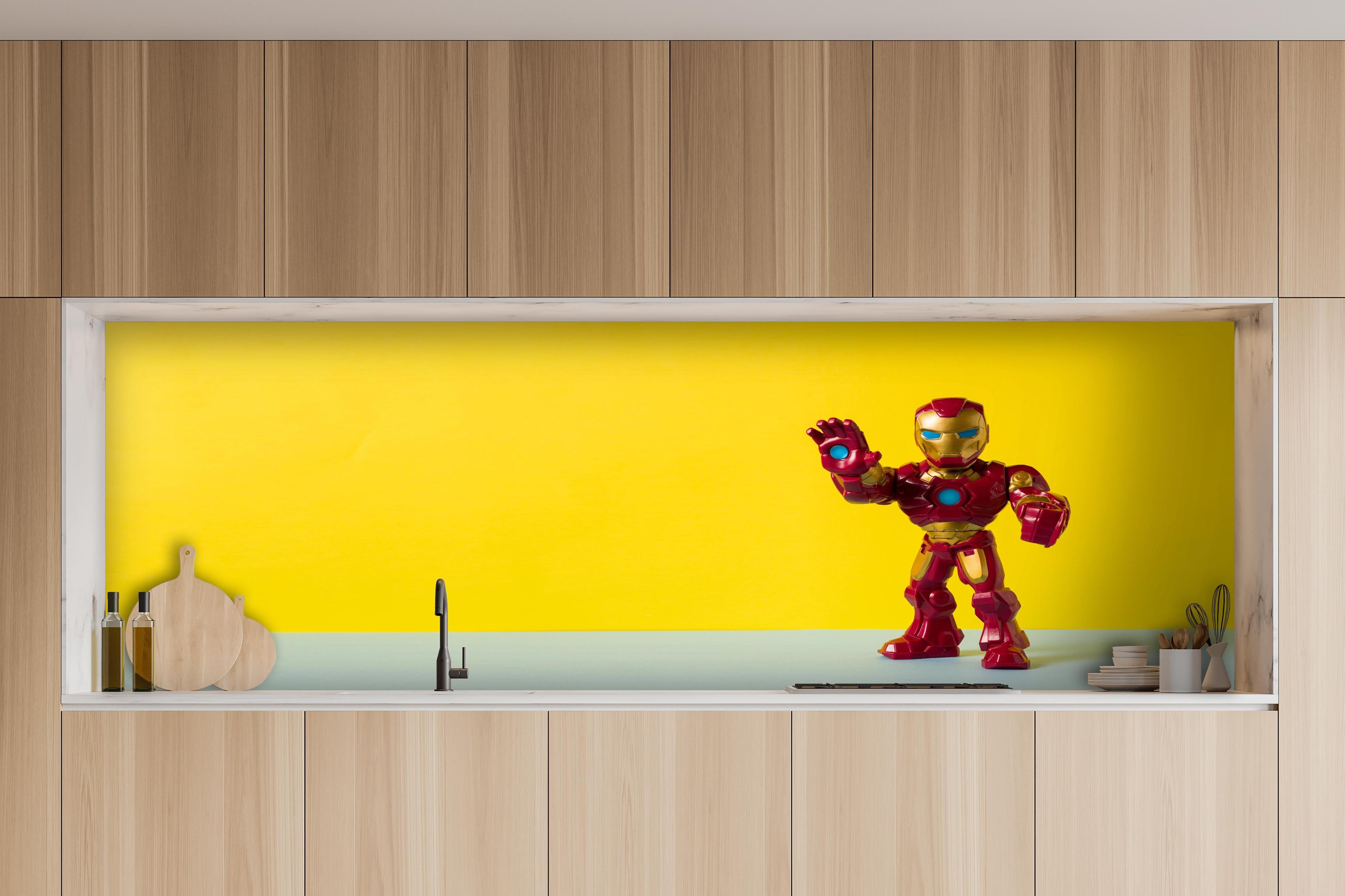 Küche - Marvel Iron Man Sammelfigur auf Gelb hinter weißen Hochglanz-Küchenregalen und schwarzem Wasserhahn