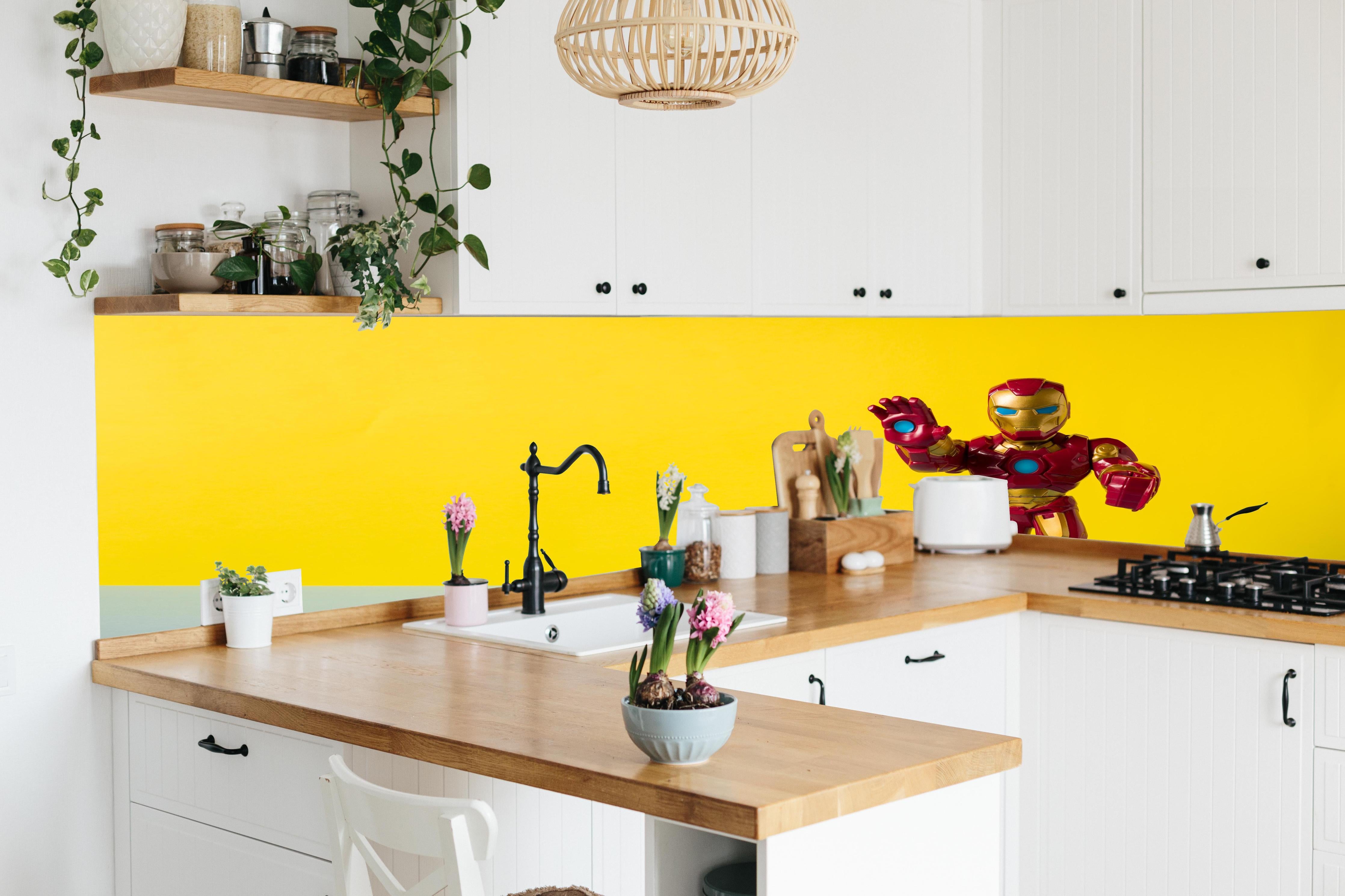 Küche - Marvel Iron Man Sammelfigur auf Gelb hinter weißen Hochglanz-Küchenregalen und schwarzem Wasserhahn