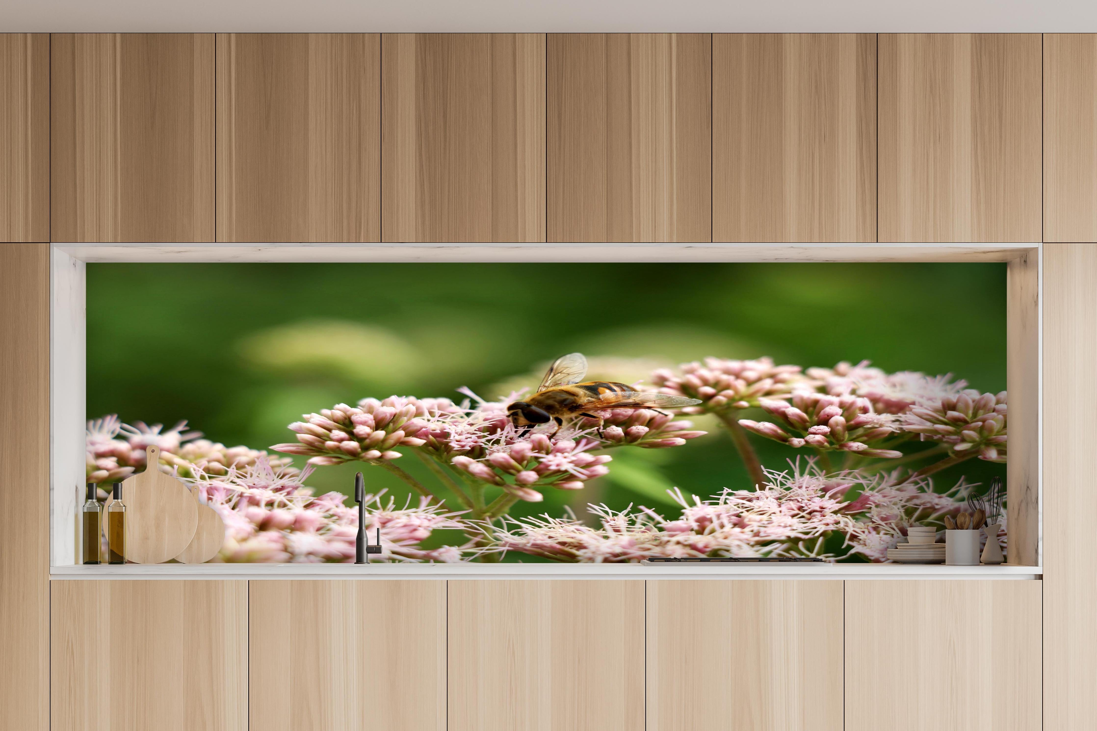 Küche - Nahaufnahme Biene Rosa Blütenpracht hinter weißen Hochglanz-Küchenregalen und schwarzem Wasserhahn