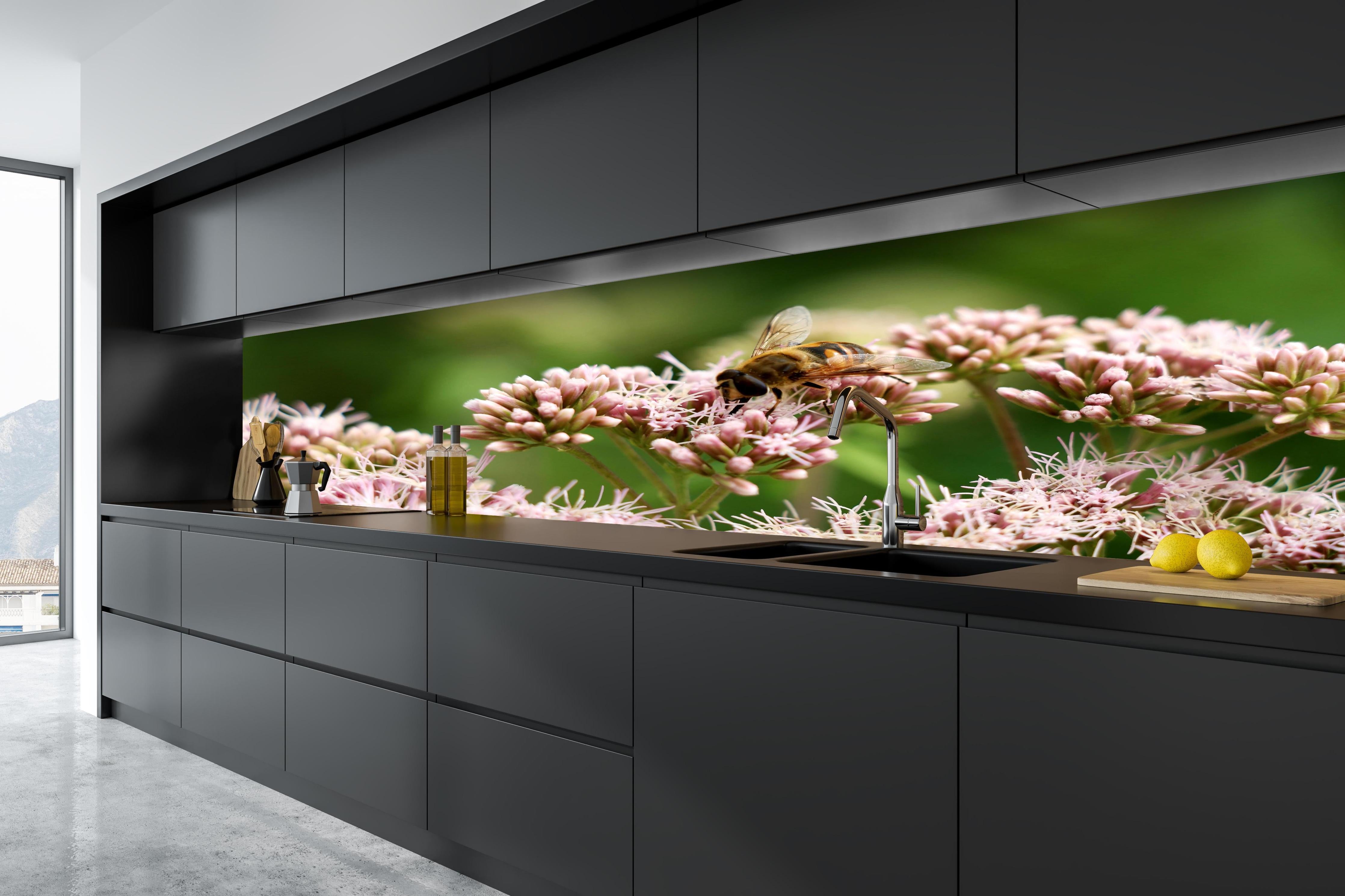 Küche - Nahaufnahme Biene Rosa Blütenpracht hinter weißen Hochglanz-Küchenregalen und schwarzem Wasserhahn