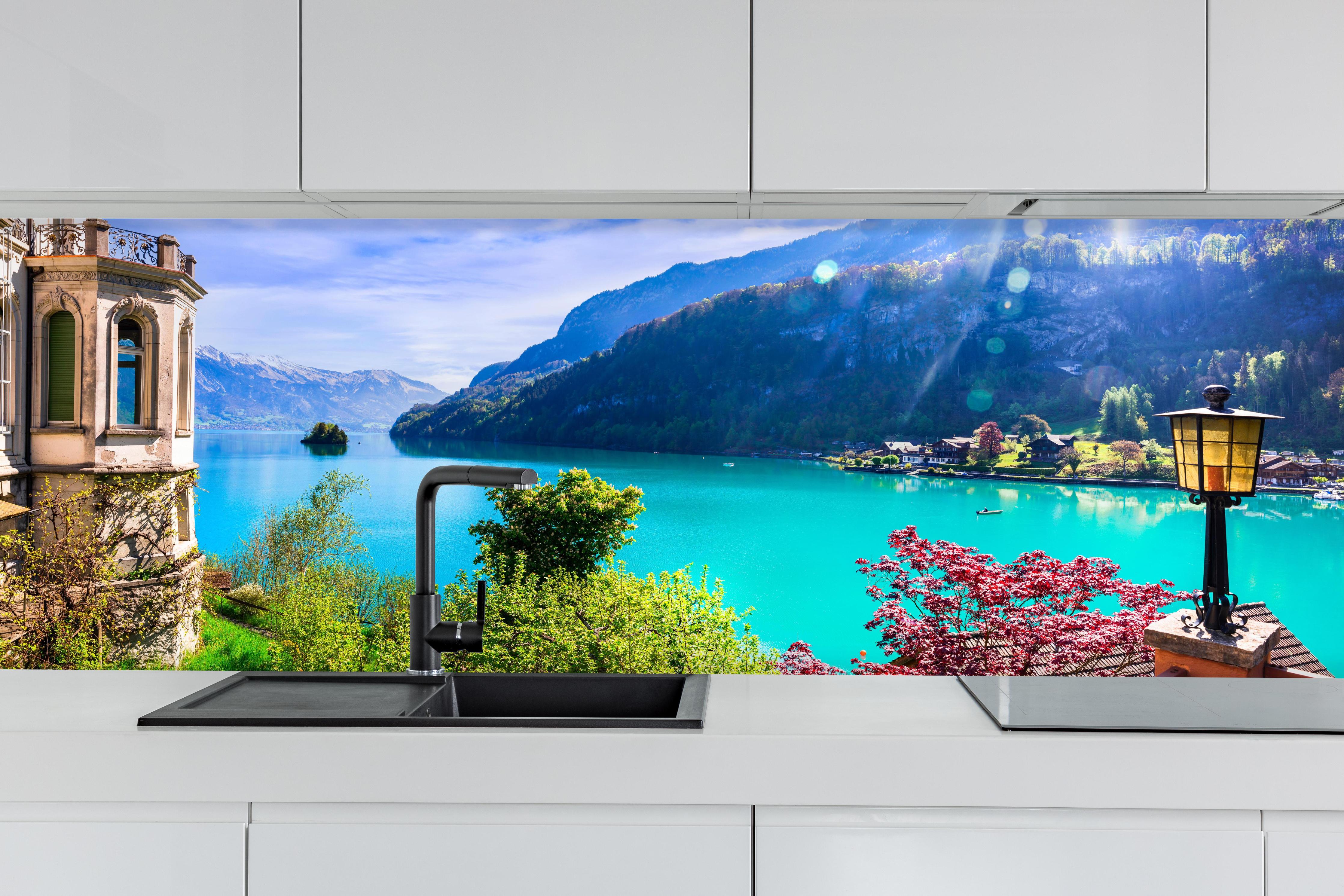 Küche - Naturkulisse des Brienzersees - Schweiz hinter weißen Hochglanz-Küchenregalen und schwarzem Wasserhahn