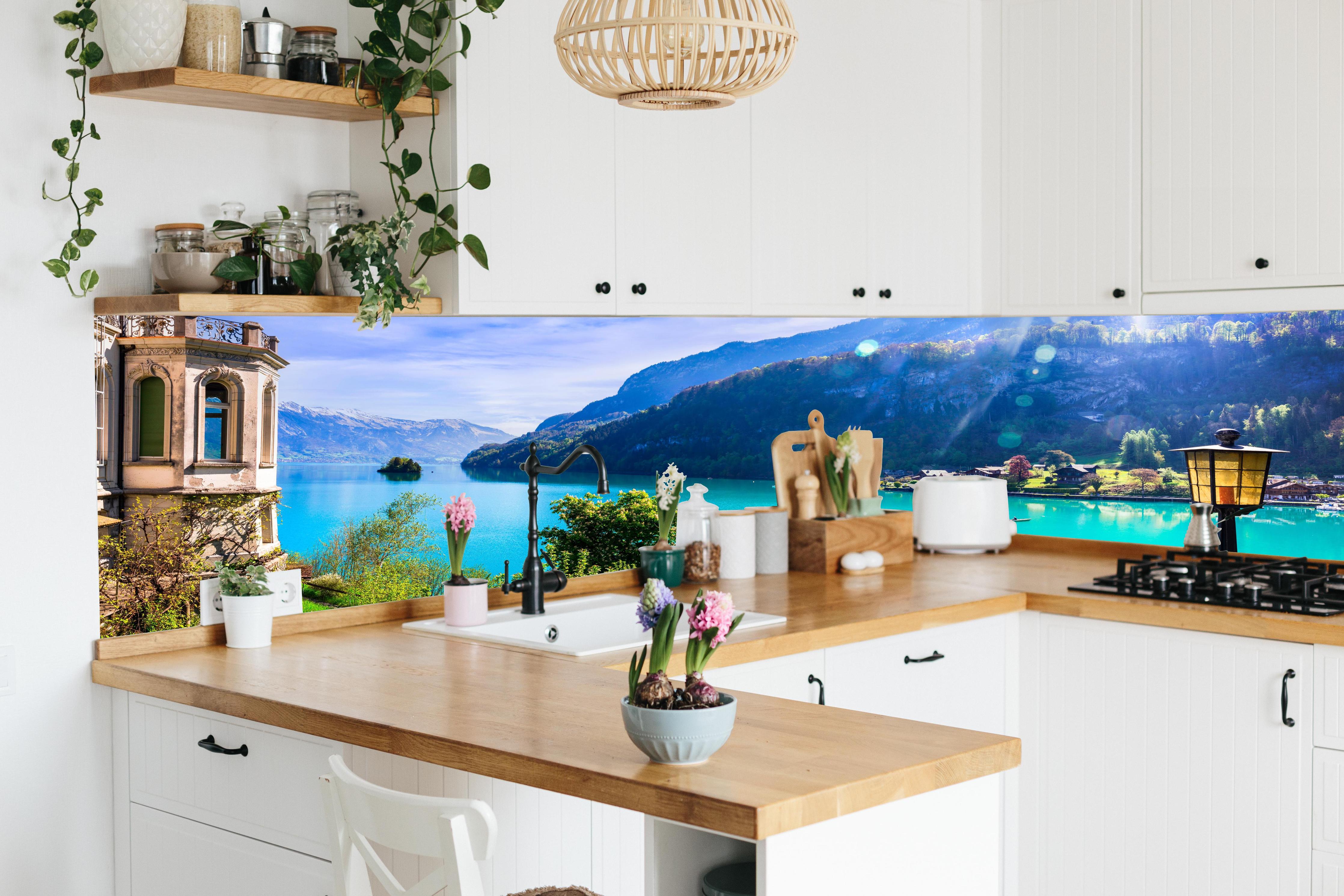 Küche - Naturkulisse des Brienzersees - Schweiz hinter weißen Hochglanz-Küchenregalen und schwarzem Wasserhahn