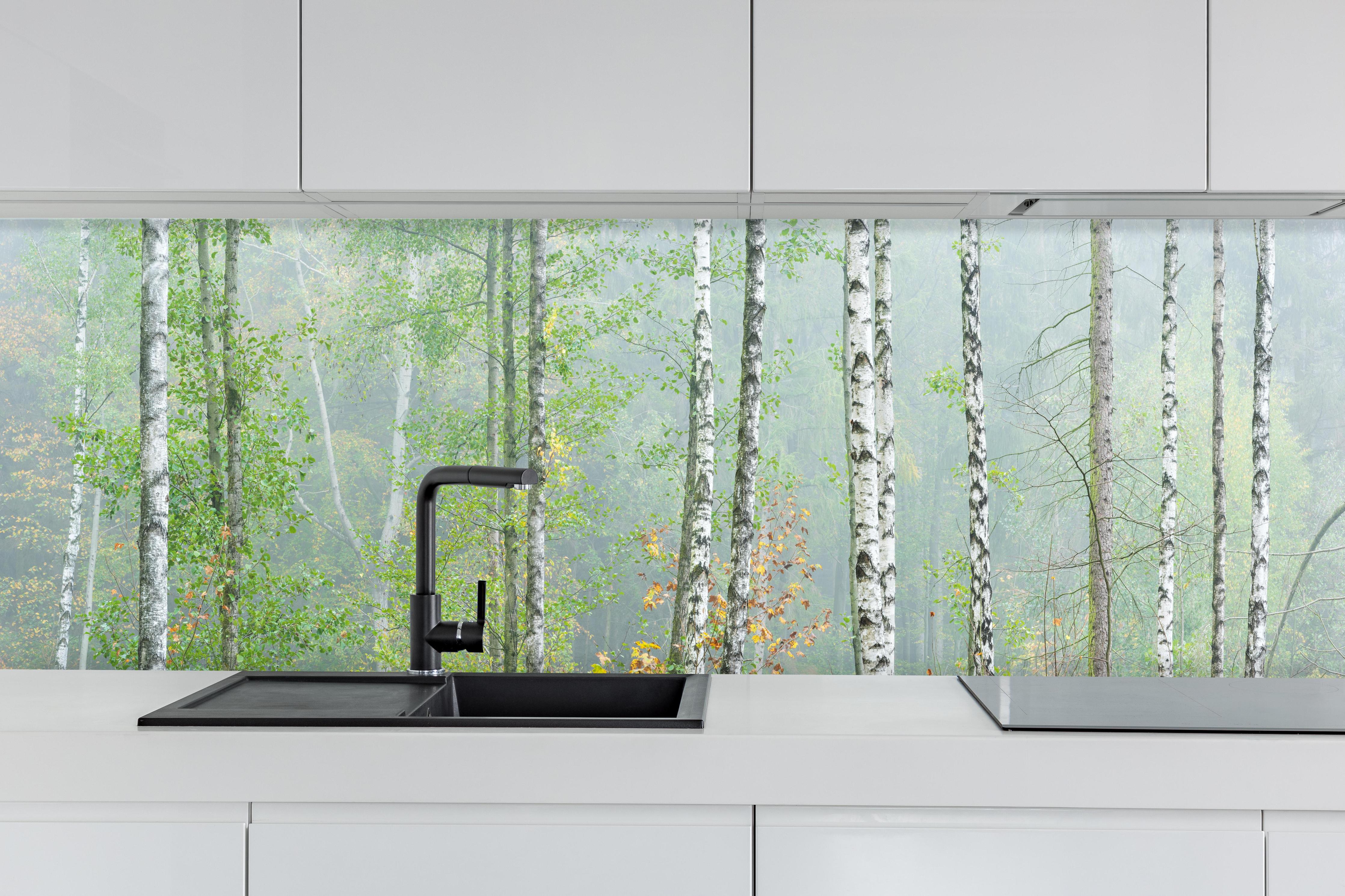 Küche - Nebeliger Birkenwald hinter weißen Hochglanz-Küchenregalen und schwarzem Wasserhahn