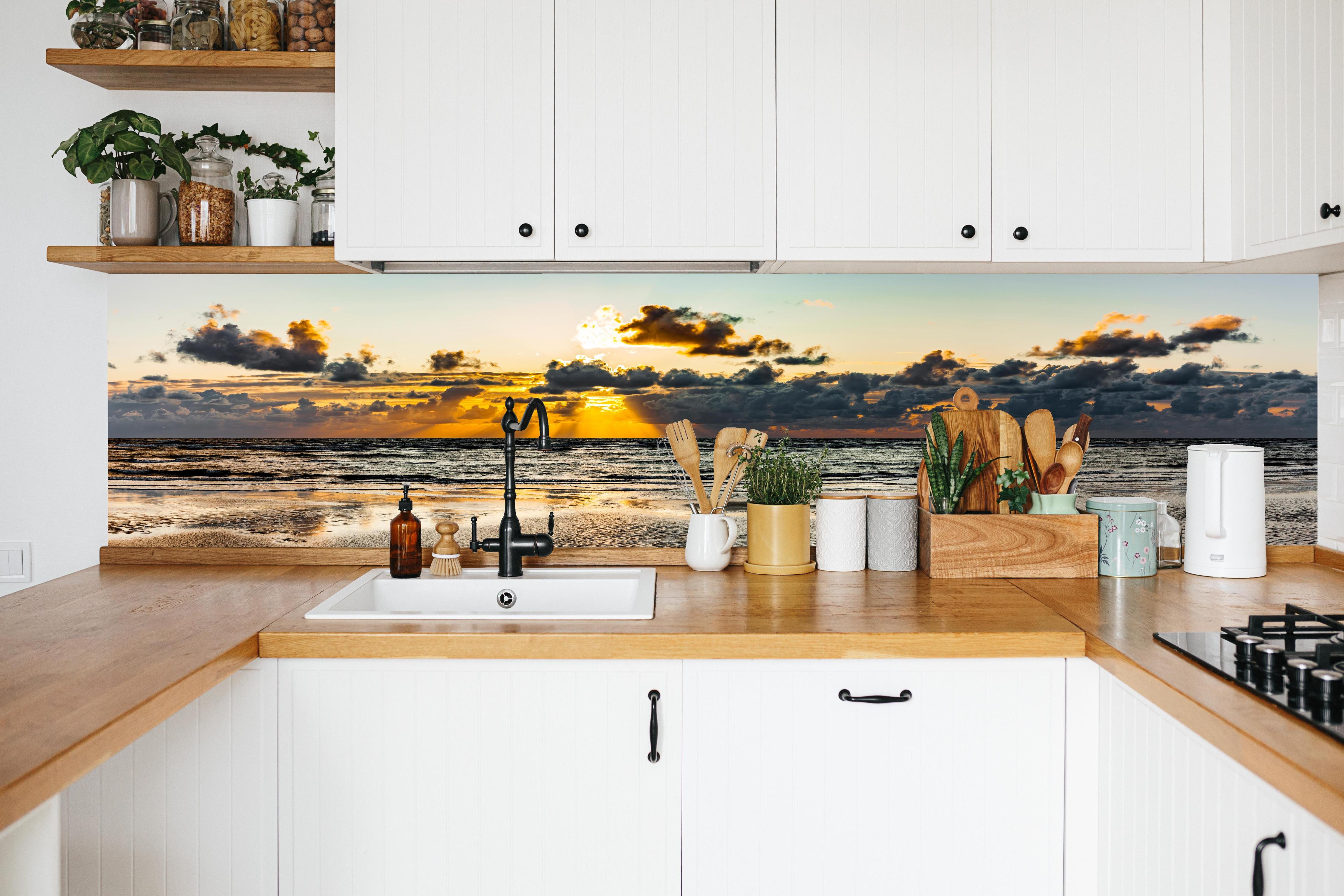 Küche - Panoramablick auf Sonnenuntergang über dem ruhigen Ozean hinter weißen Hochglanz-Küchenregalen und schwarzem Wasserhahn