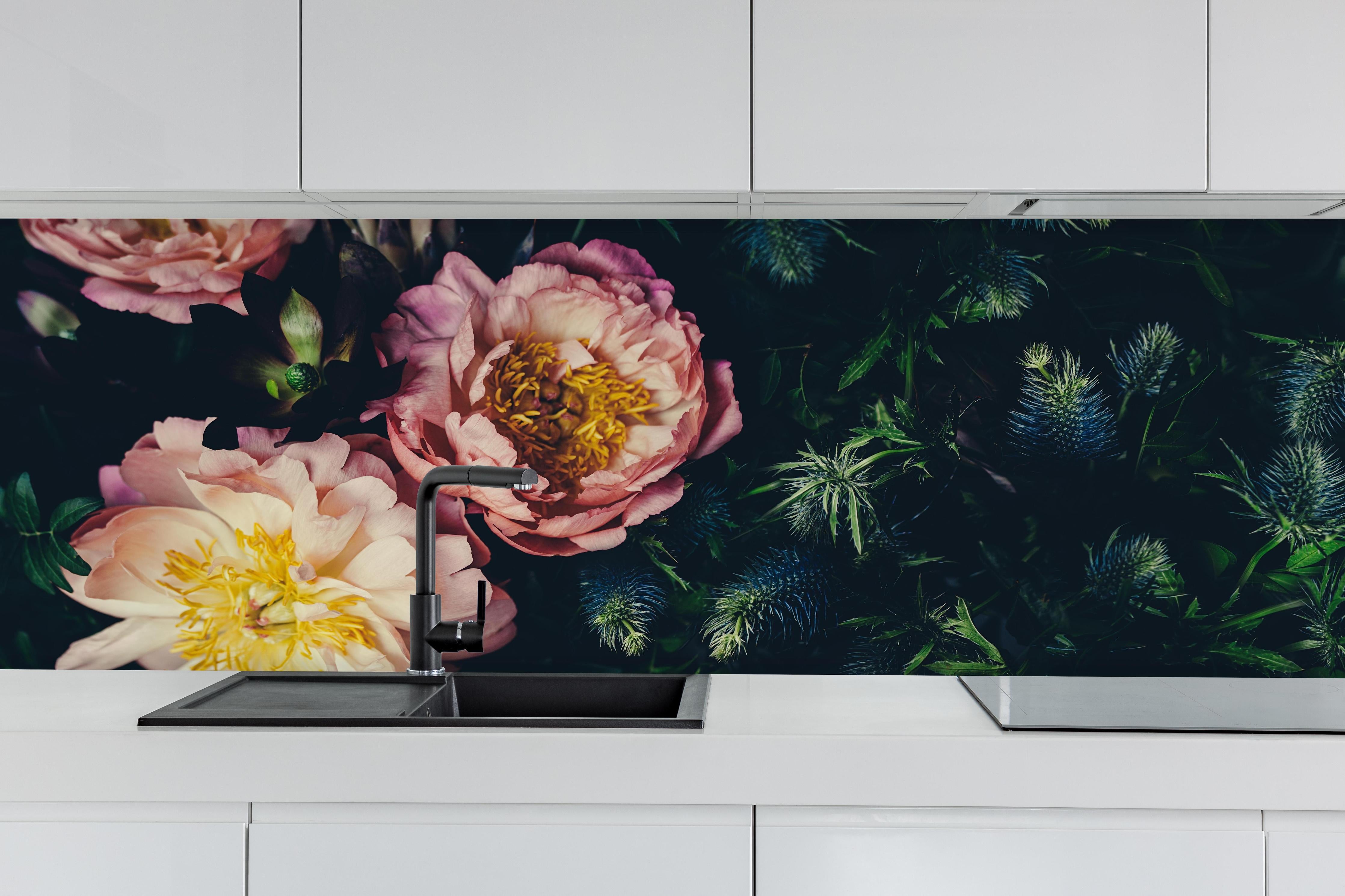 Küche - Rosa Blüten auf einer Wiese hinter weißen Hochglanz-Küchenregalen und schwarzem Wasserhahn