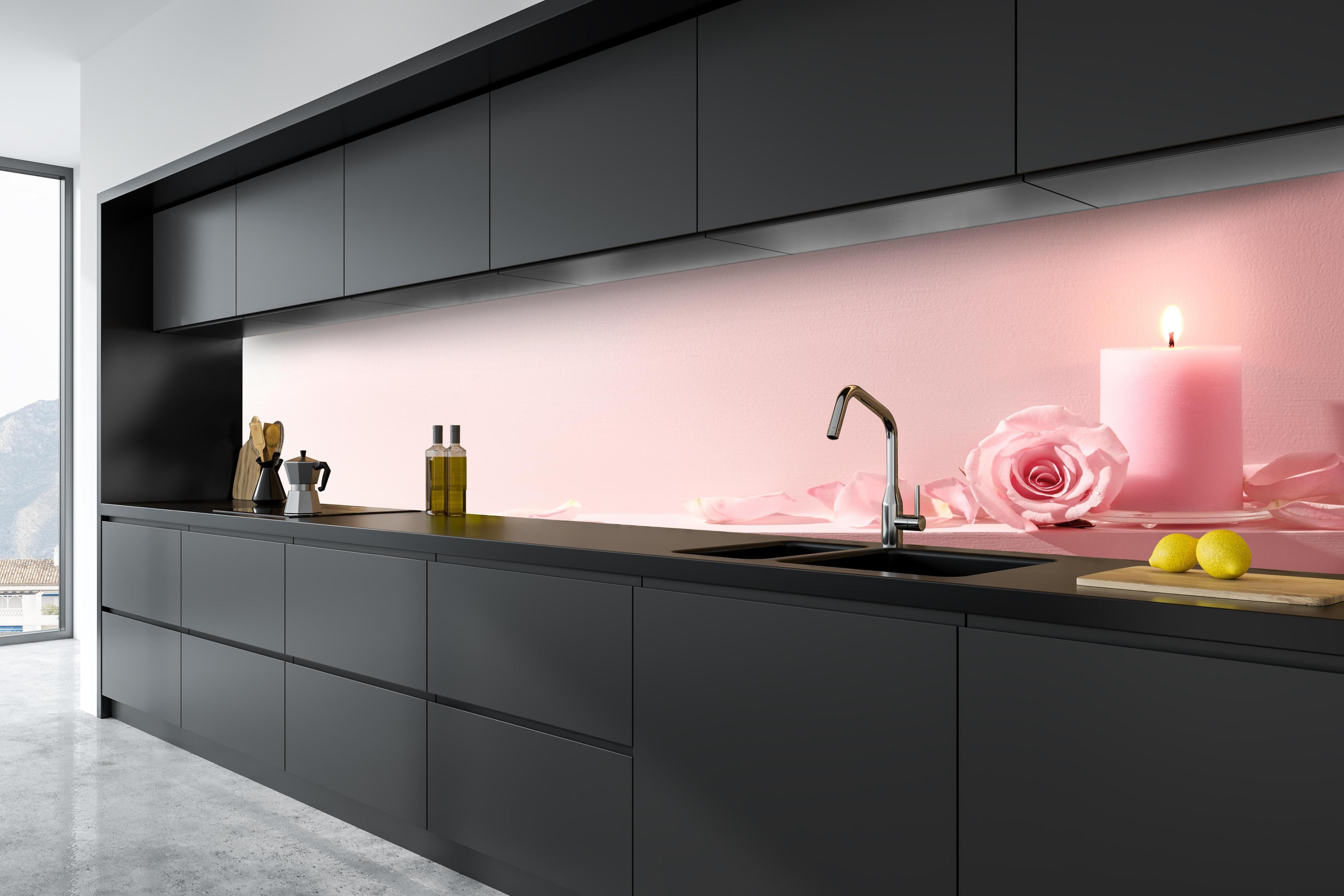 Küche - Rosa Rosen und Kerze auf einem rosa Hintergrund hinter weißen Hochglanz-Küchenregalen und schwarzem Wasserhahn