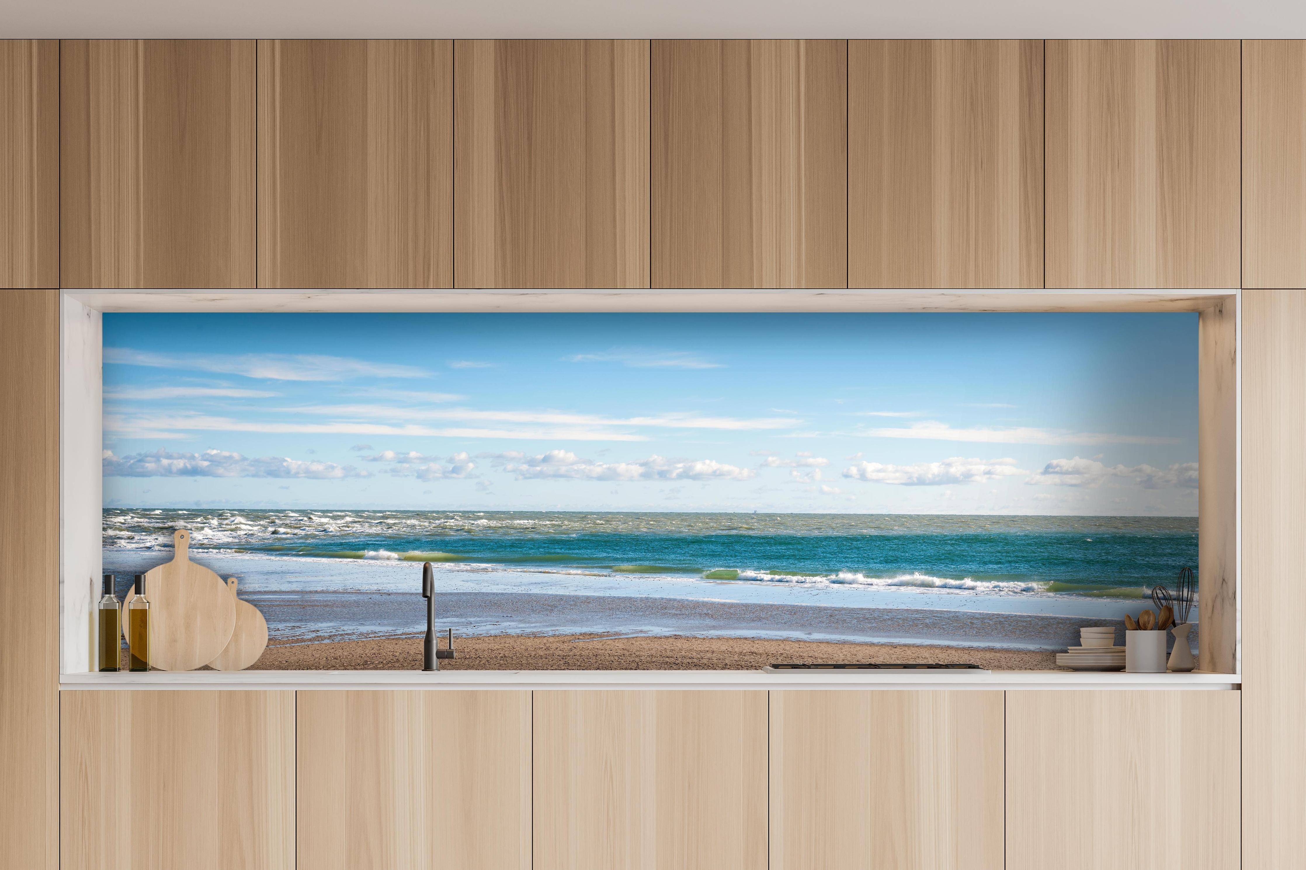 Küche - Ruhige Küstenlandschaft unter blauem Himmel mit sanften Wellen und feinem Sand hinter weißen Hochglanz-Küchenregalen und schwarzem Wasserhahn