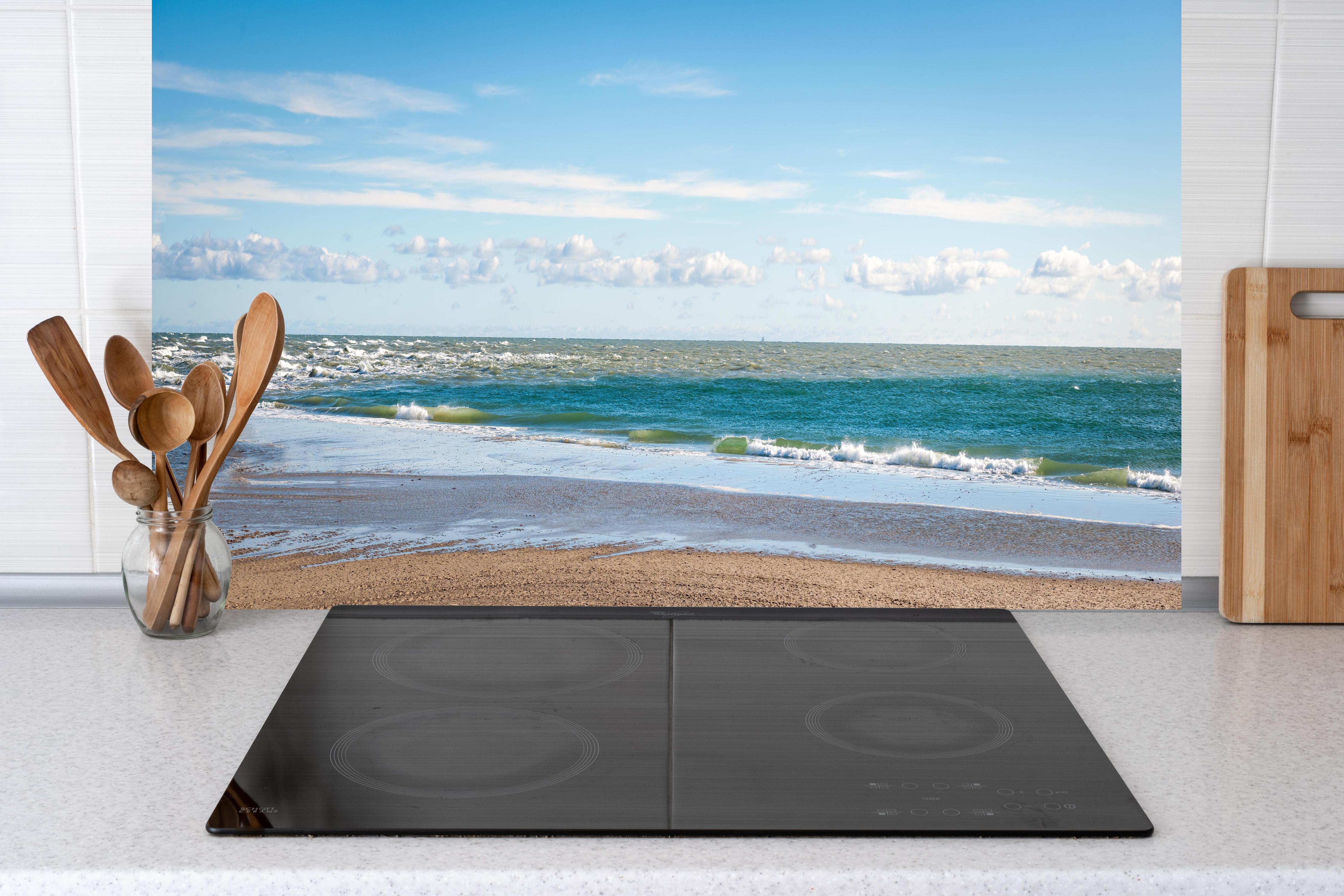 Küche - Ruhige Küstenlandschaft unter blauem Himmel mit sanften Wellen und feinem Sand hinter weißen Hochglanz-Küchenregalen und schwarzem Wasserhahn