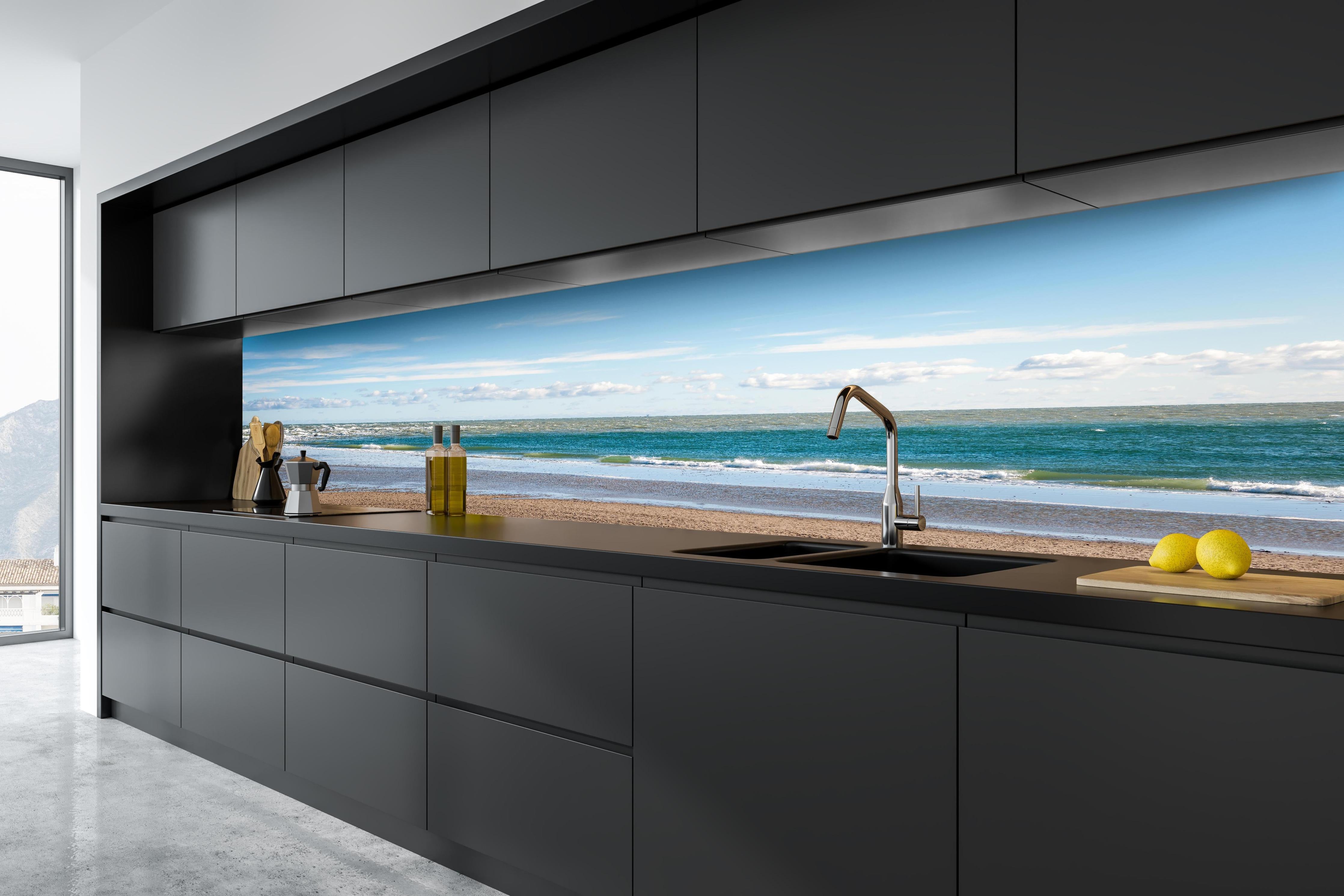 Küche - Ruhige Küstenlandschaft unter blauem Himmel mit sanften Wellen und feinem Sand hinter weißen Hochglanz-Küchenregalen und schwarzem Wasserhahn
