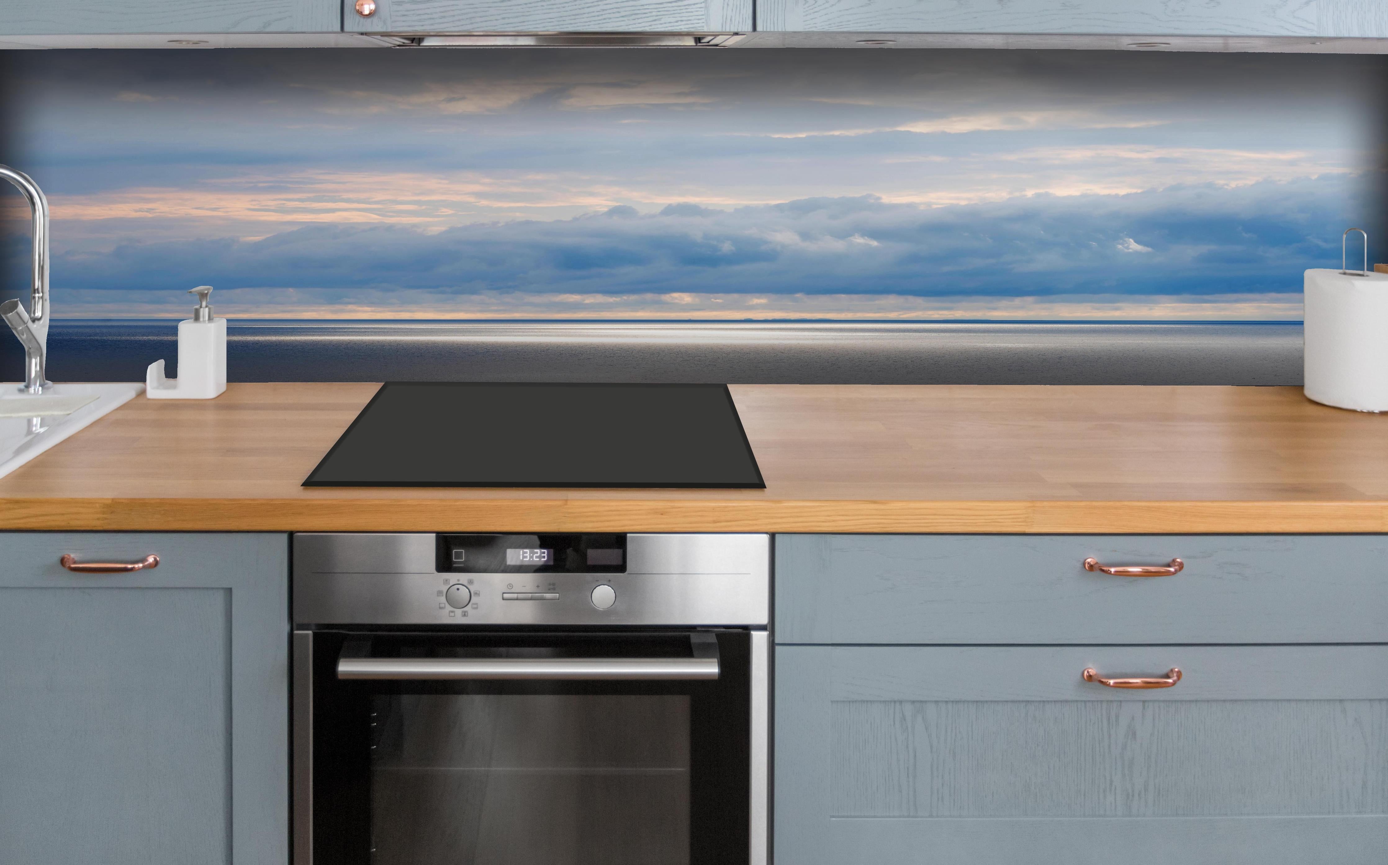 Küche - Ruhiges Blau-Grau-Meerespanorama mit sanften Wellen und Wolken hinter weißen Hochglanz-Küchenregalen und schwarzem Wasserhahn