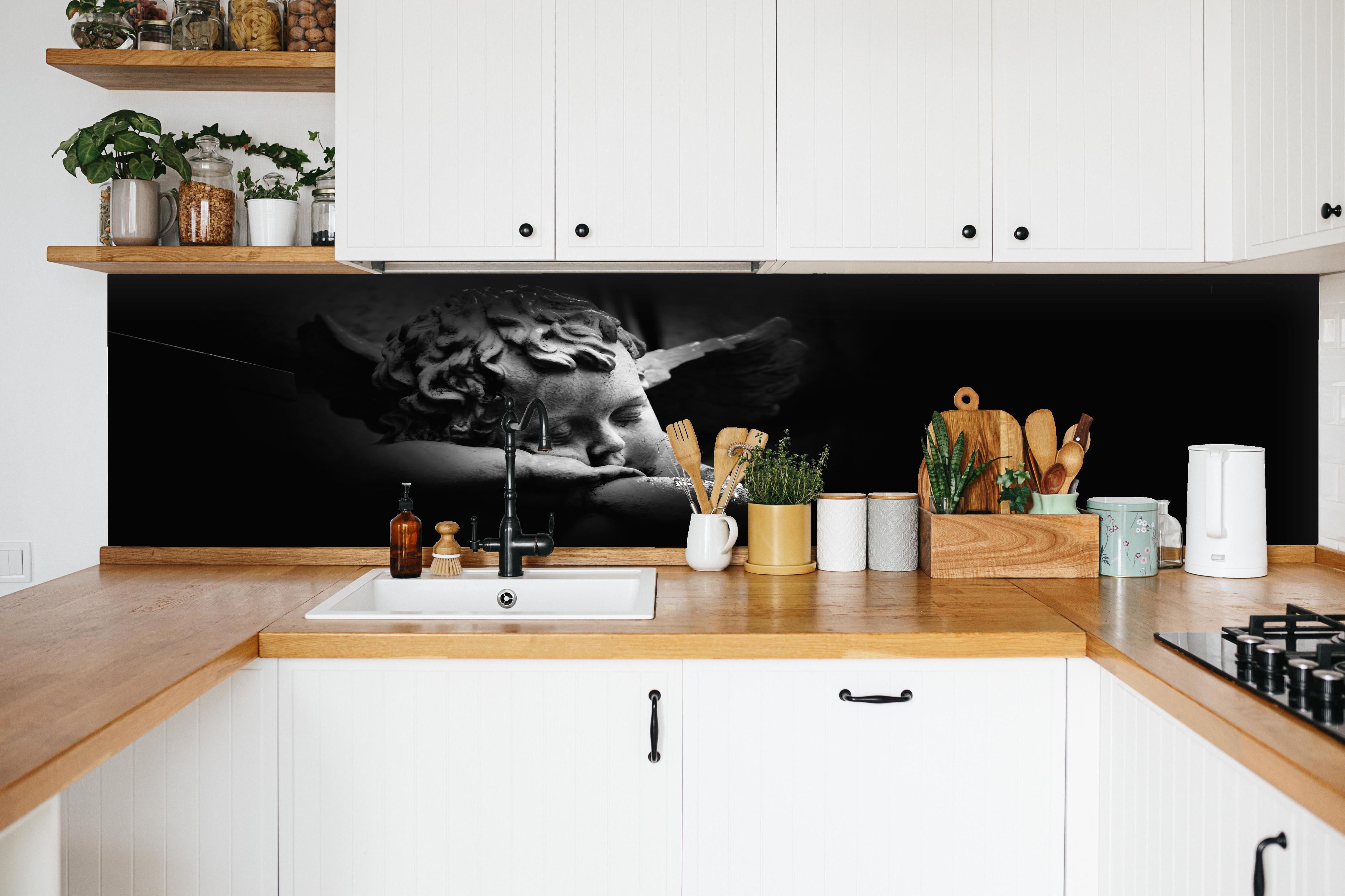 Küche - Schlafender Engel Statue in Schwarz-Weiß hinter weißen Hochglanz-Küchenregalen und schwarzem Wasserhahn