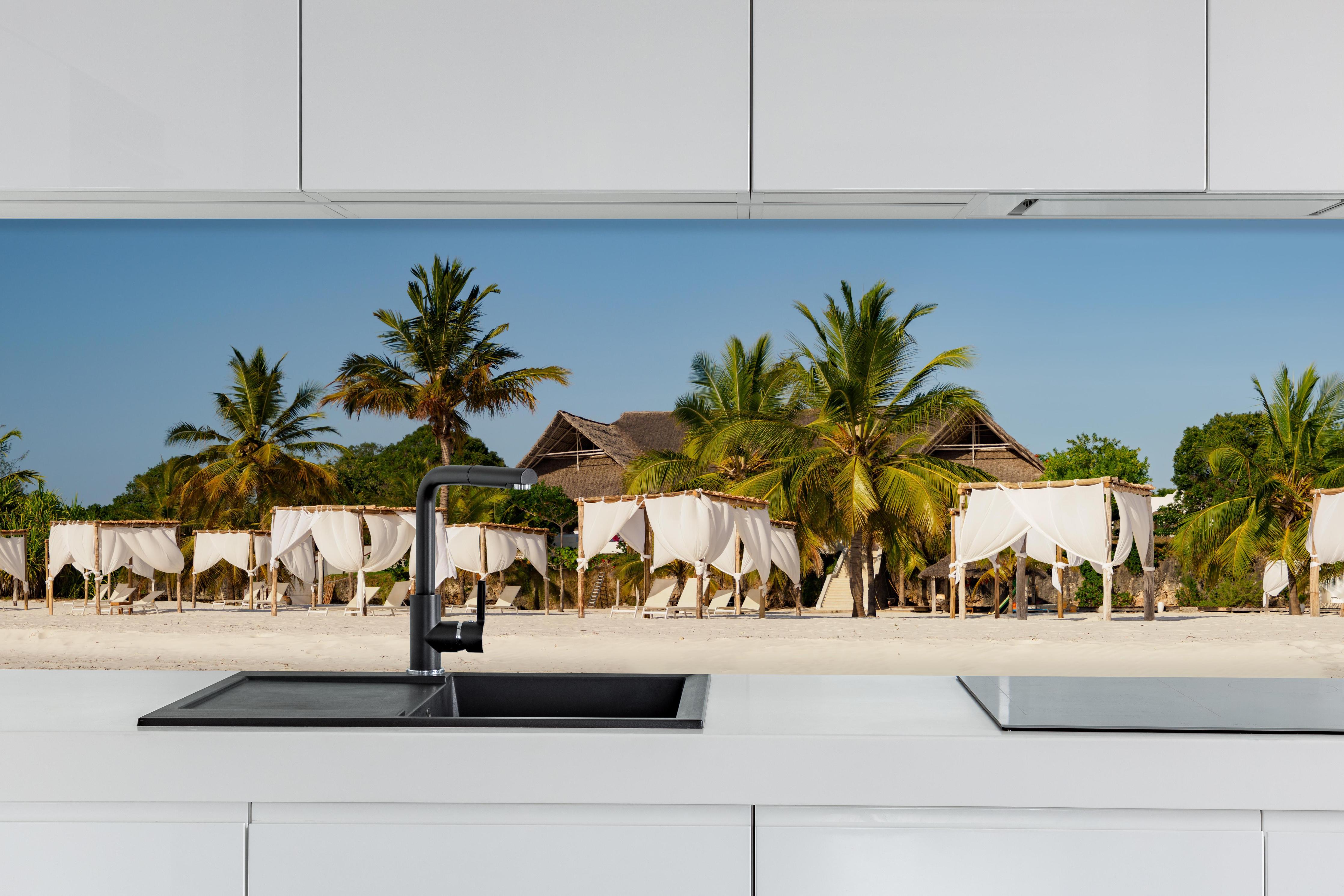 Küche - Schöner Strand mit Liegen hinter weißen Hochglanz-Küchenregalen und schwarzem Wasserhahn