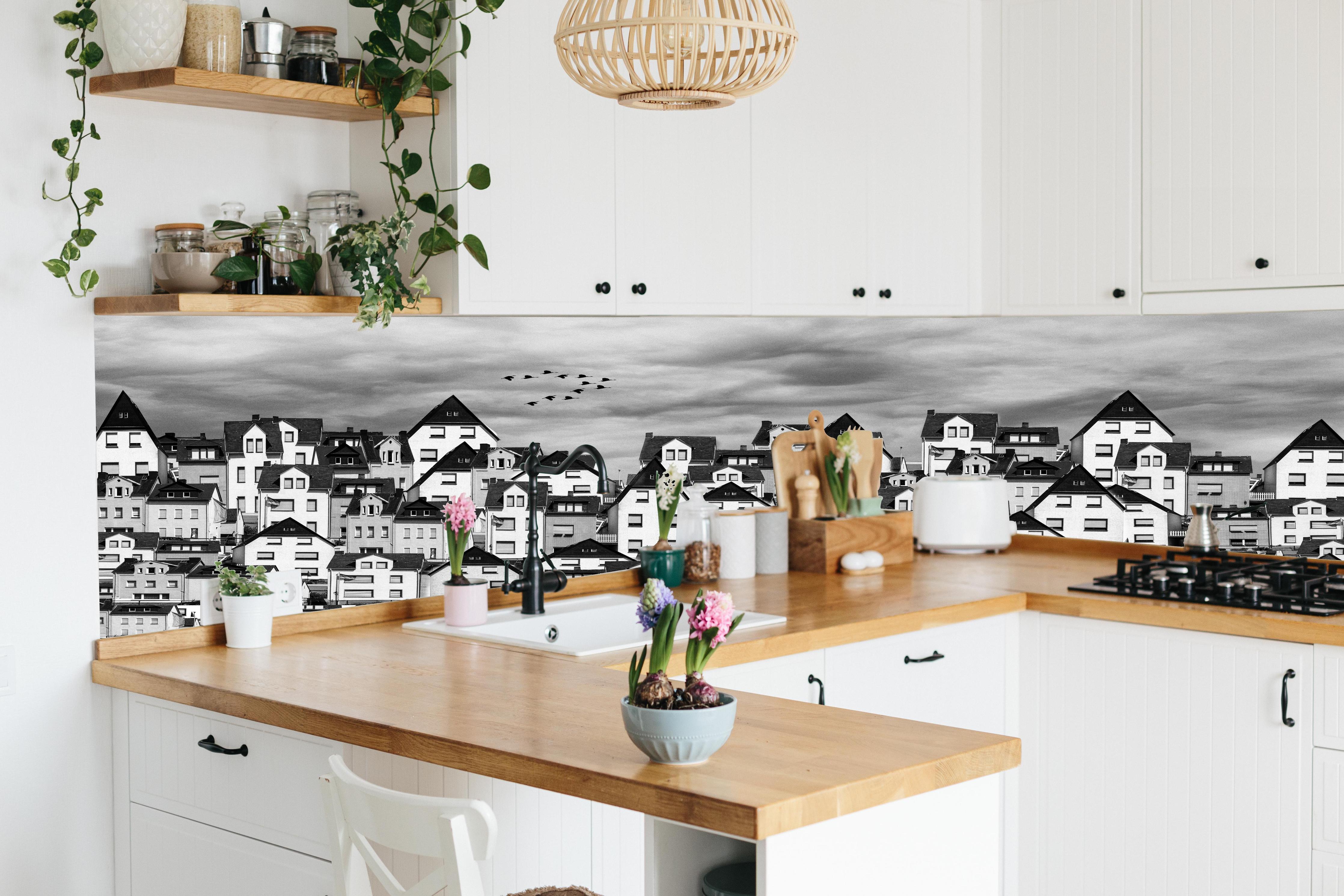 Küche - Schwarz-weiße Dachlandschaft mit Vögeln hinter weißen Hochglanz-Küchenregalen und schwarzem Wasserhahn