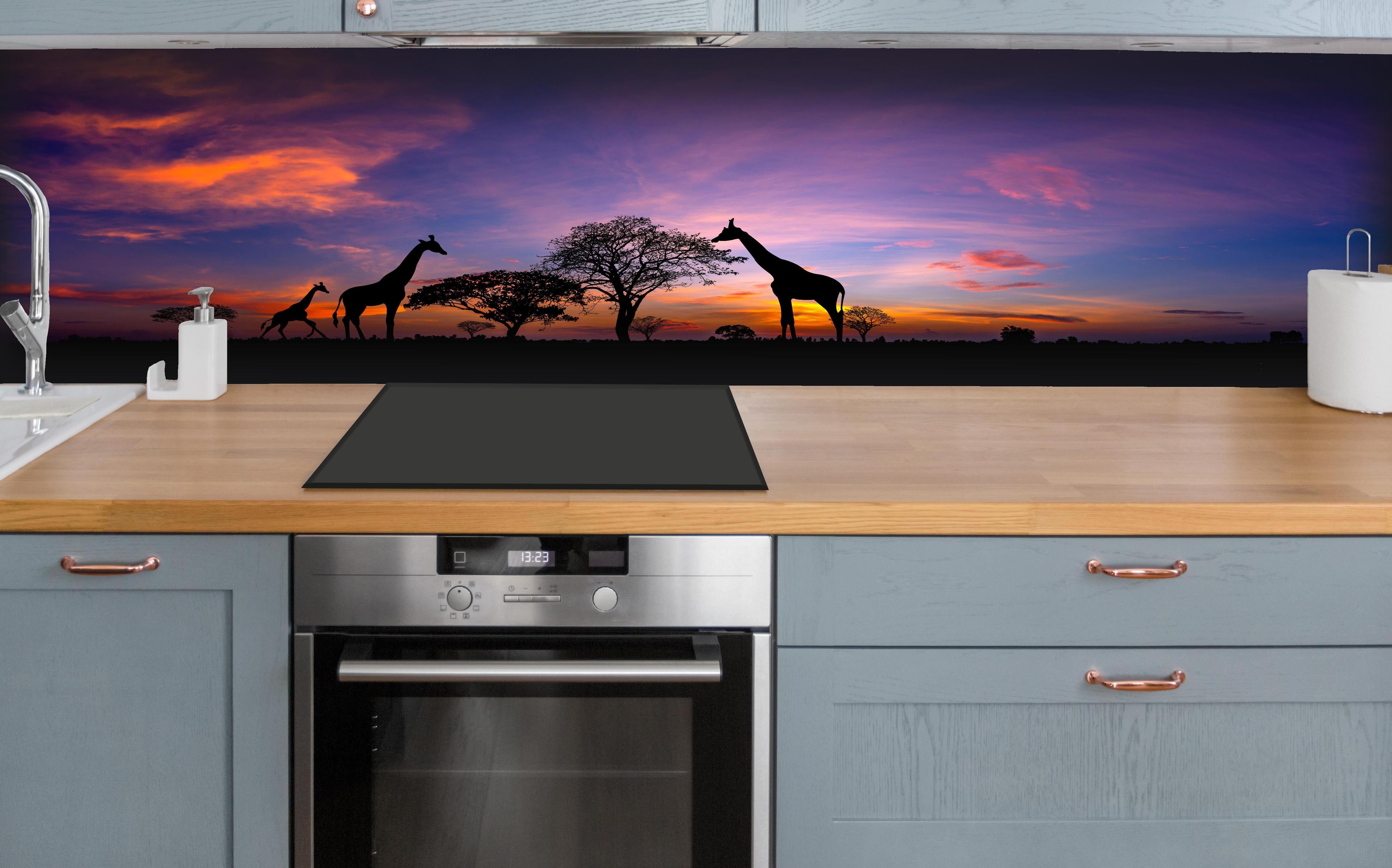 Küche - Silhouette - Giraffenfamilie bei Sonnenuntergang hinter weißen Hochglanz-Küchenregalen und schwarzem Wasserhahn