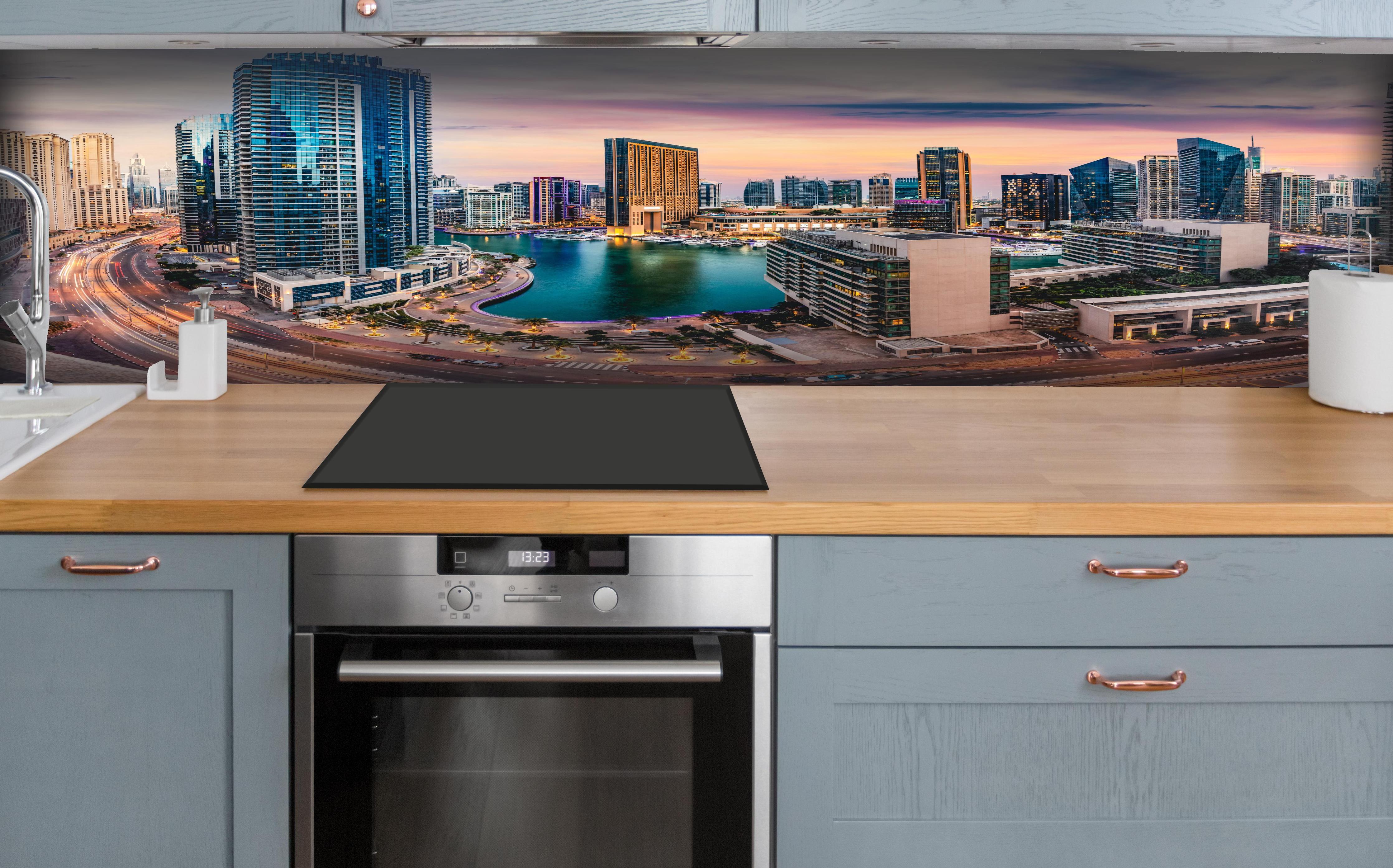 Küche - Skyline des Jachthafens von Dubai bei Sonnenuntergang hinter weißen Hochglanz-Küchenregalen und schwarzem Wasserhahn