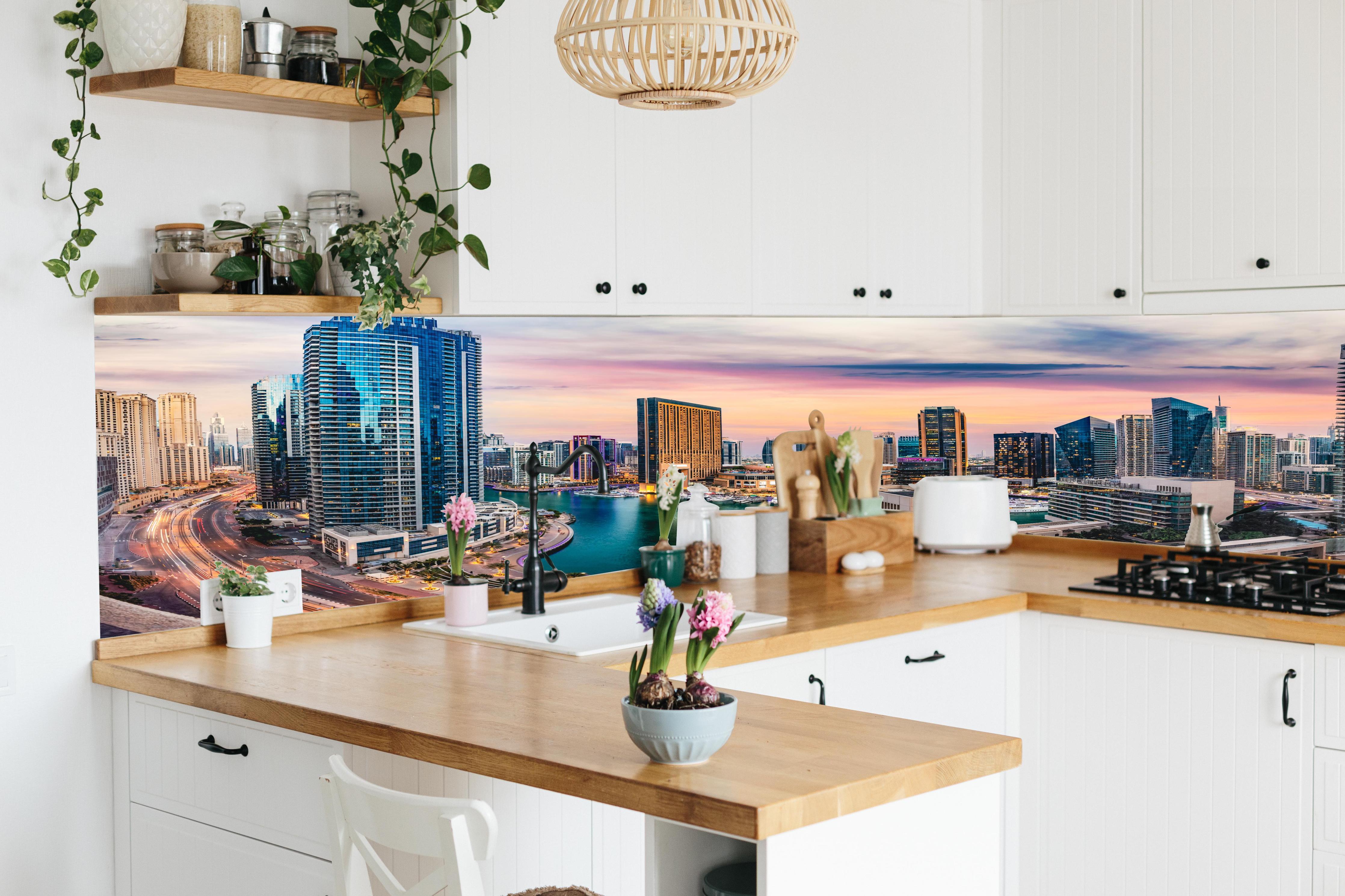 Küche - Skyline des Jachthafens von Dubai bei Sonnenuntergang hinter weißen Hochglanz-Küchenregalen und schwarzem Wasserhahn