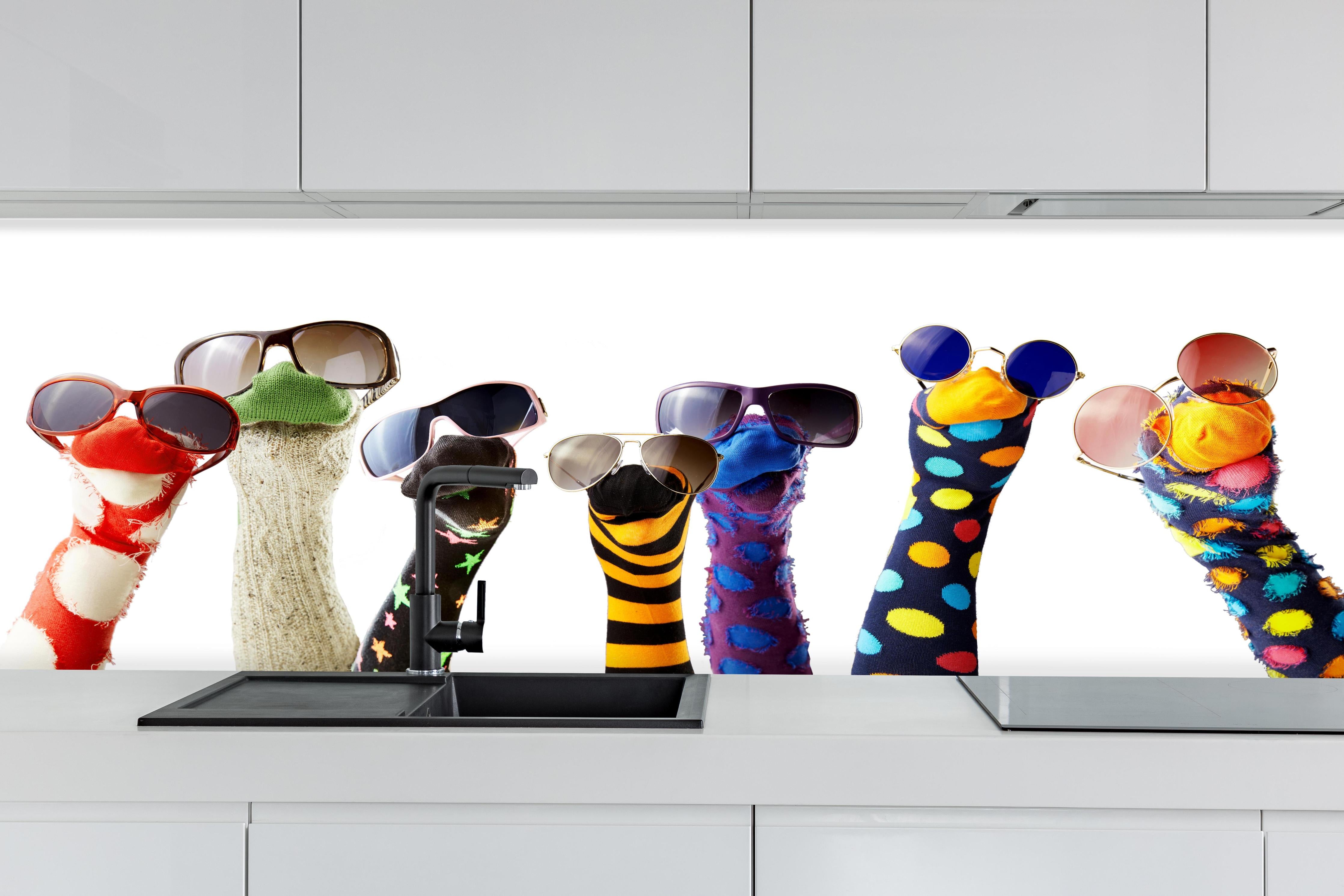 Küche - Sockenpuppen mit Brille hinter weißen Hochglanz-Küchenregalen und schwarzem Wasserhahn