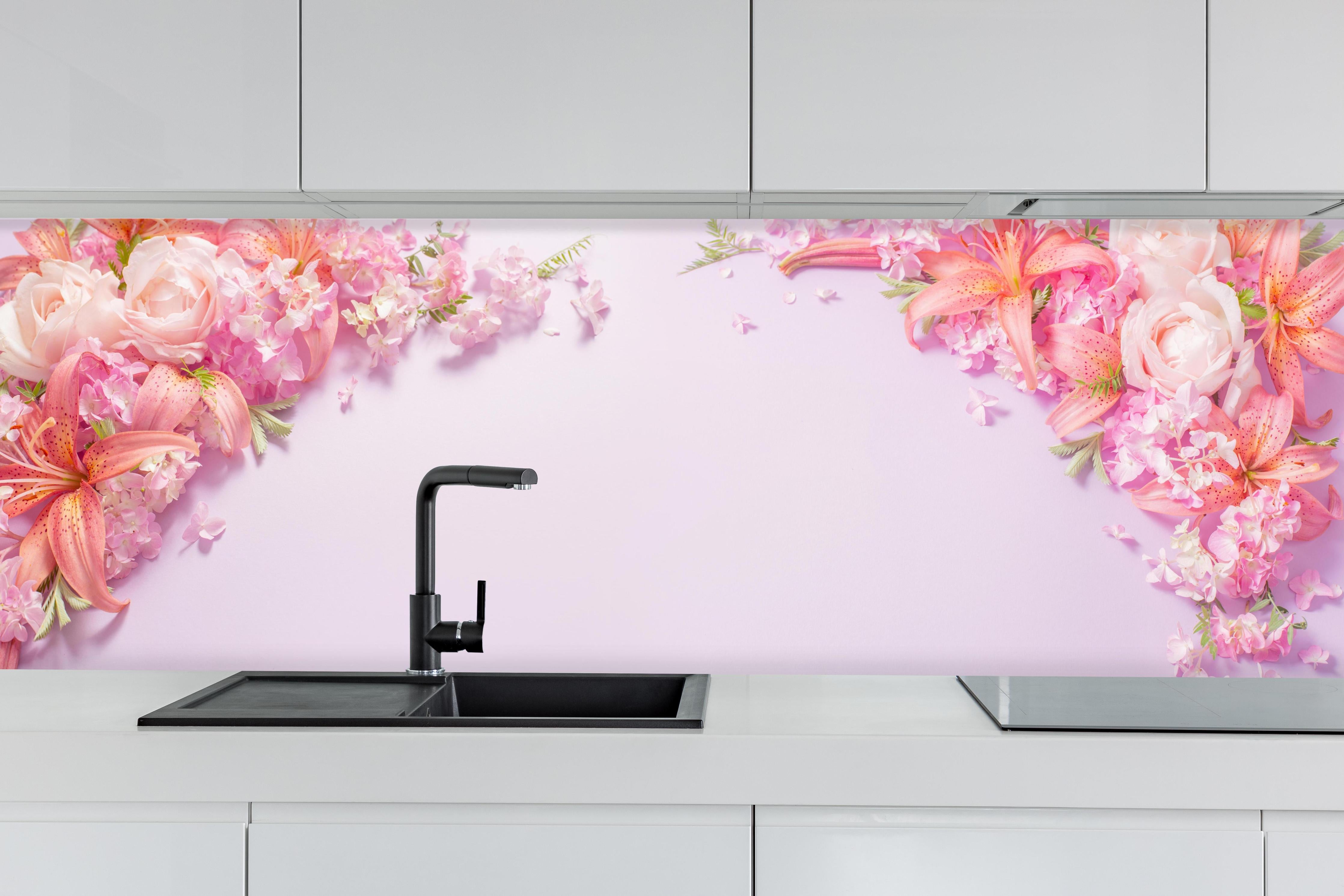 Küche - Sommerliche Blumenarrangements auf Papier hinter weißen Hochglanz-Küchenregalen und schwarzem Wasserhahn