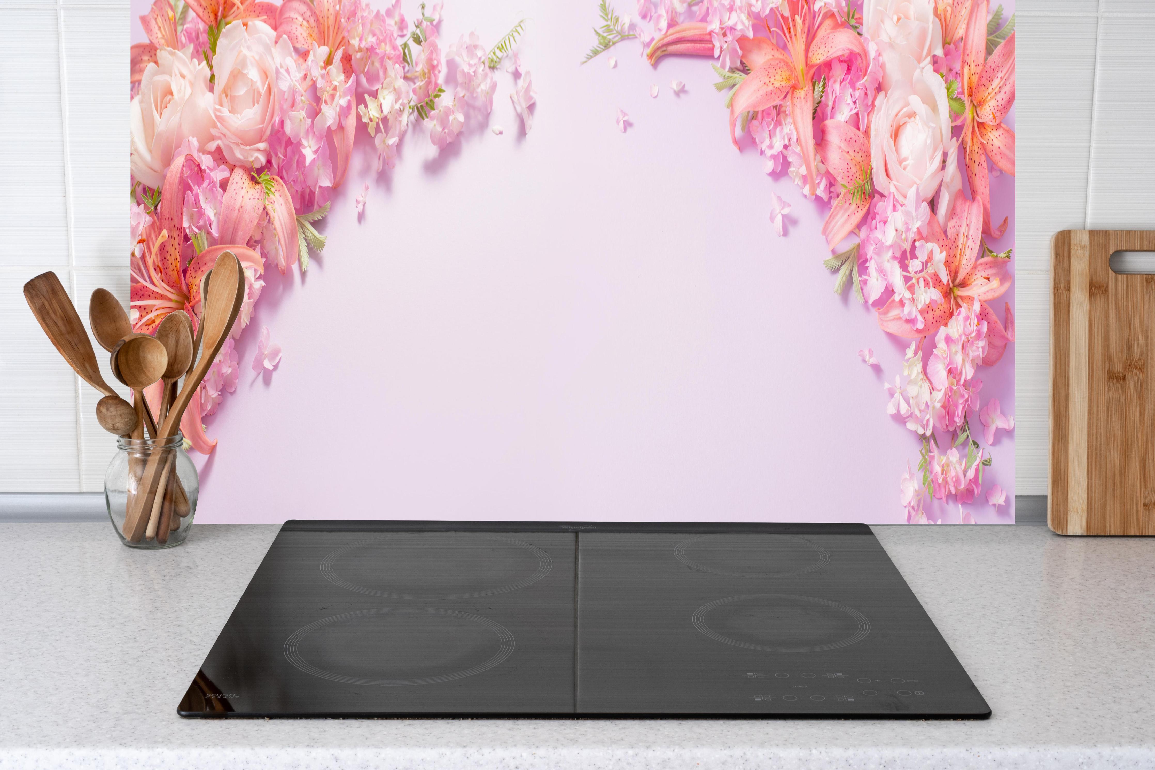 Küche - Sommerliche Blumenarrangements auf Papier hinter weißen Hochglanz-Küchenregalen und schwarzem Wasserhahn