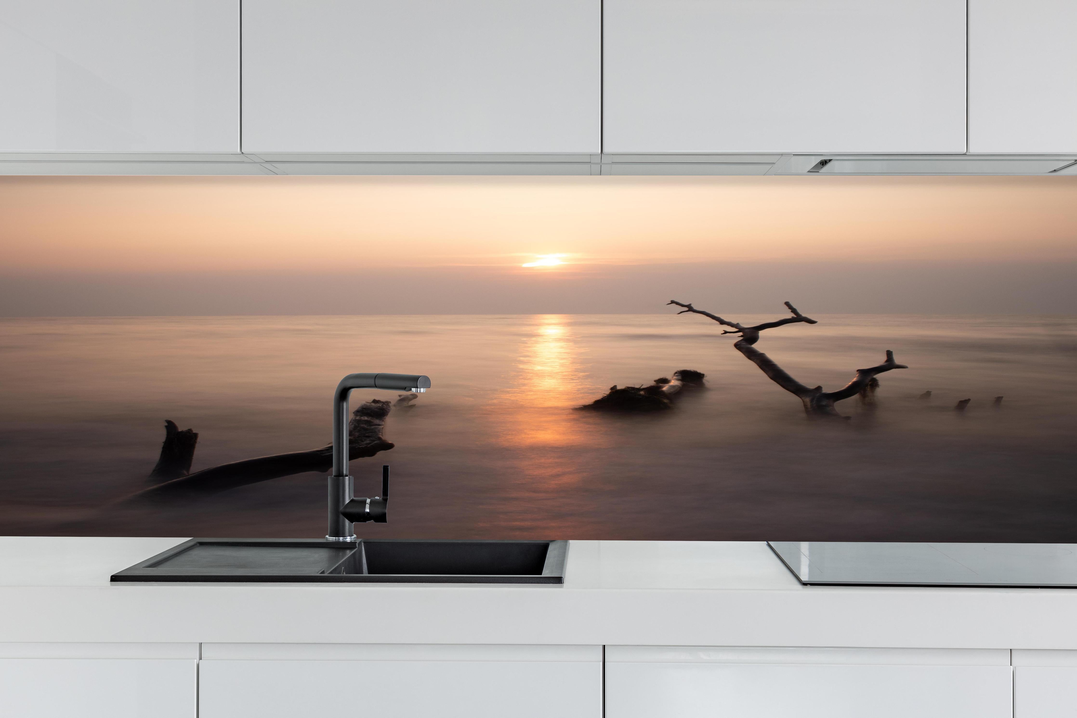 Küche - Stimmungsvoller Sonnenuntergangs-Strand hinter weißen Hochglanz-Küchenregalen und schwarzem Wasserhahn