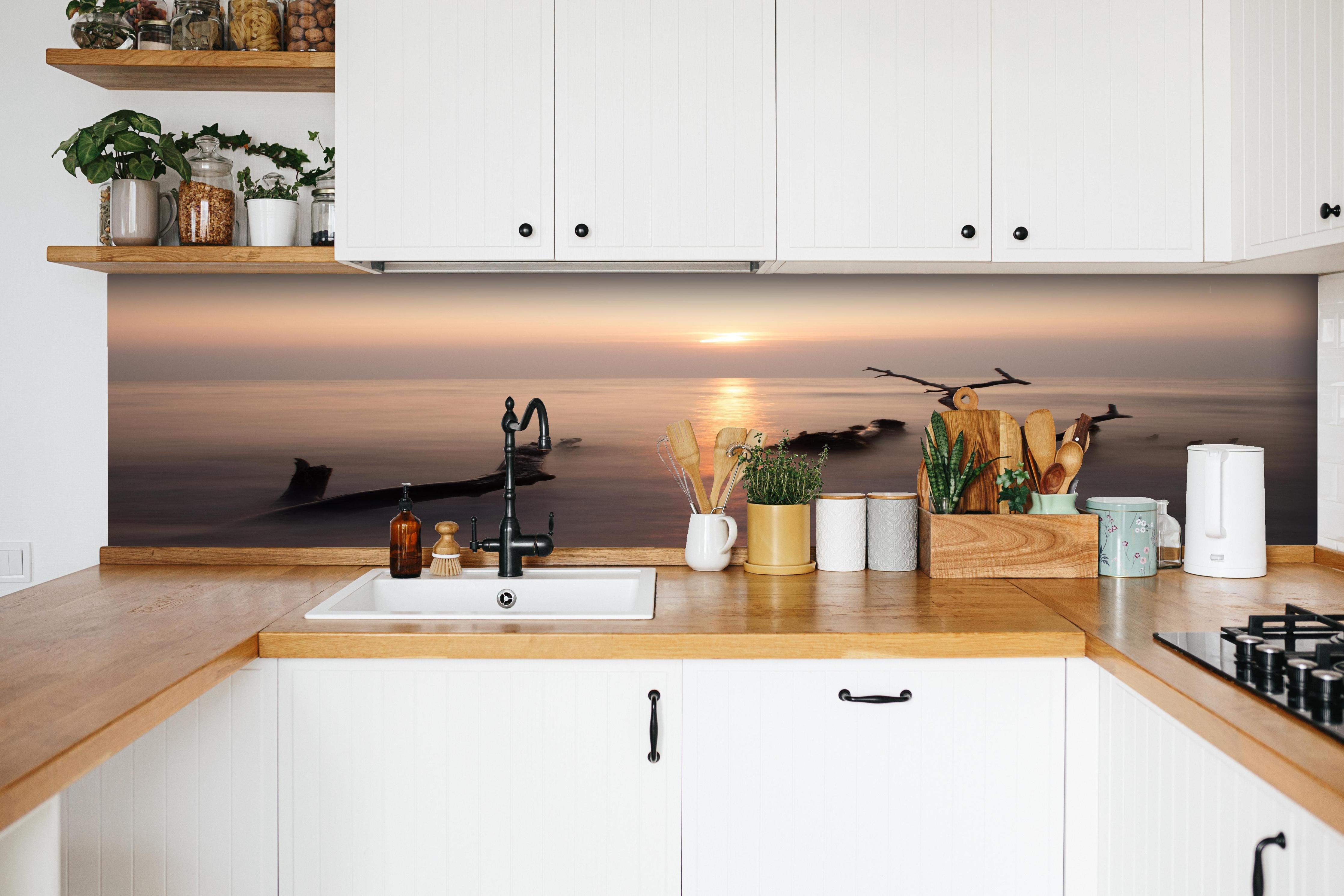 Küche - Stimmungsvoller Sonnenuntergangs-Strand hinter weißen Hochglanz-Küchenregalen und schwarzem Wasserhahn