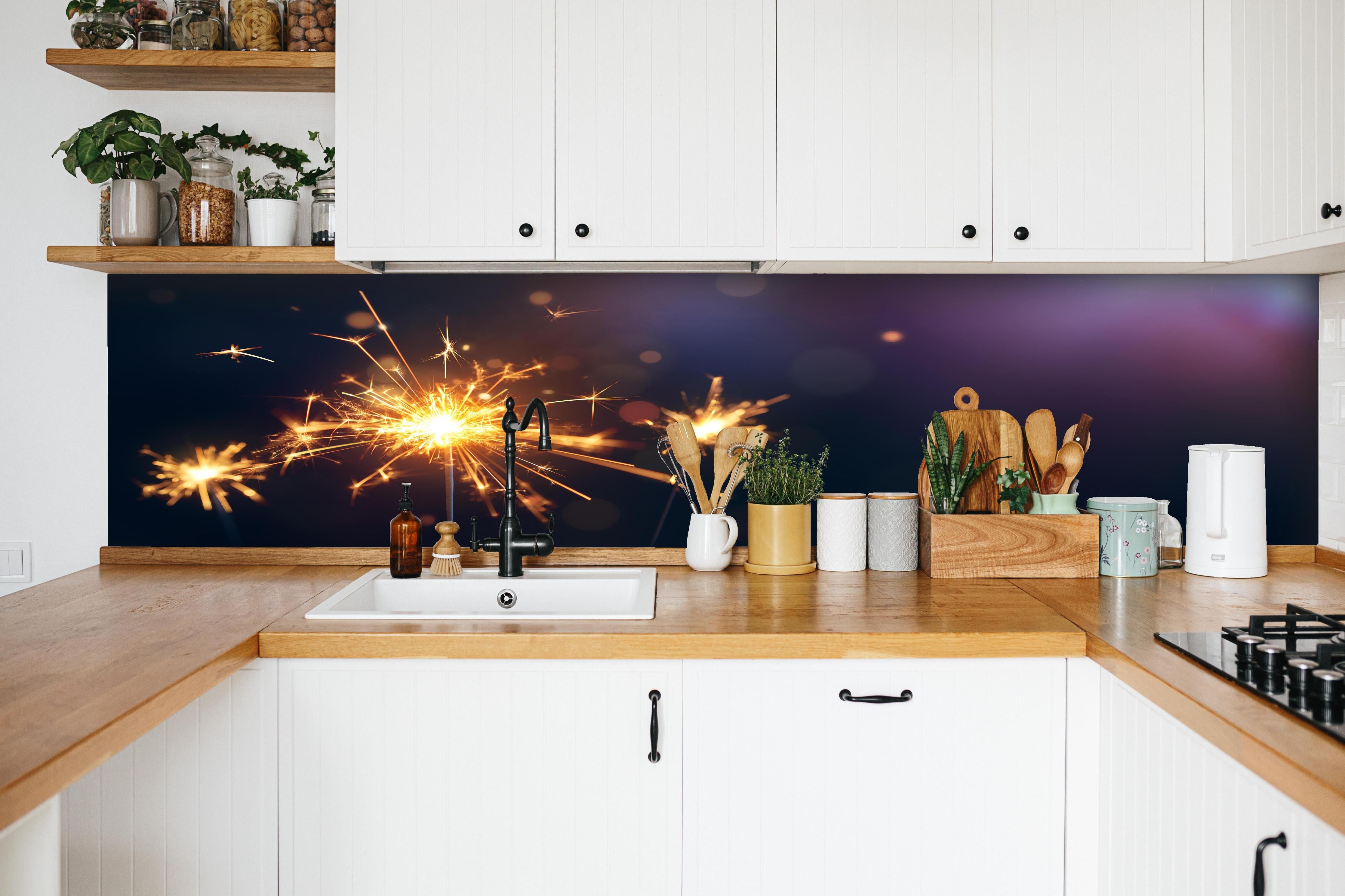 Küche - Strahlendes Wunderkerzen-Goldlichtfeuerwerk hinter weißen Hochglanz-Küchenregalen und schwarzem Wasserhahn