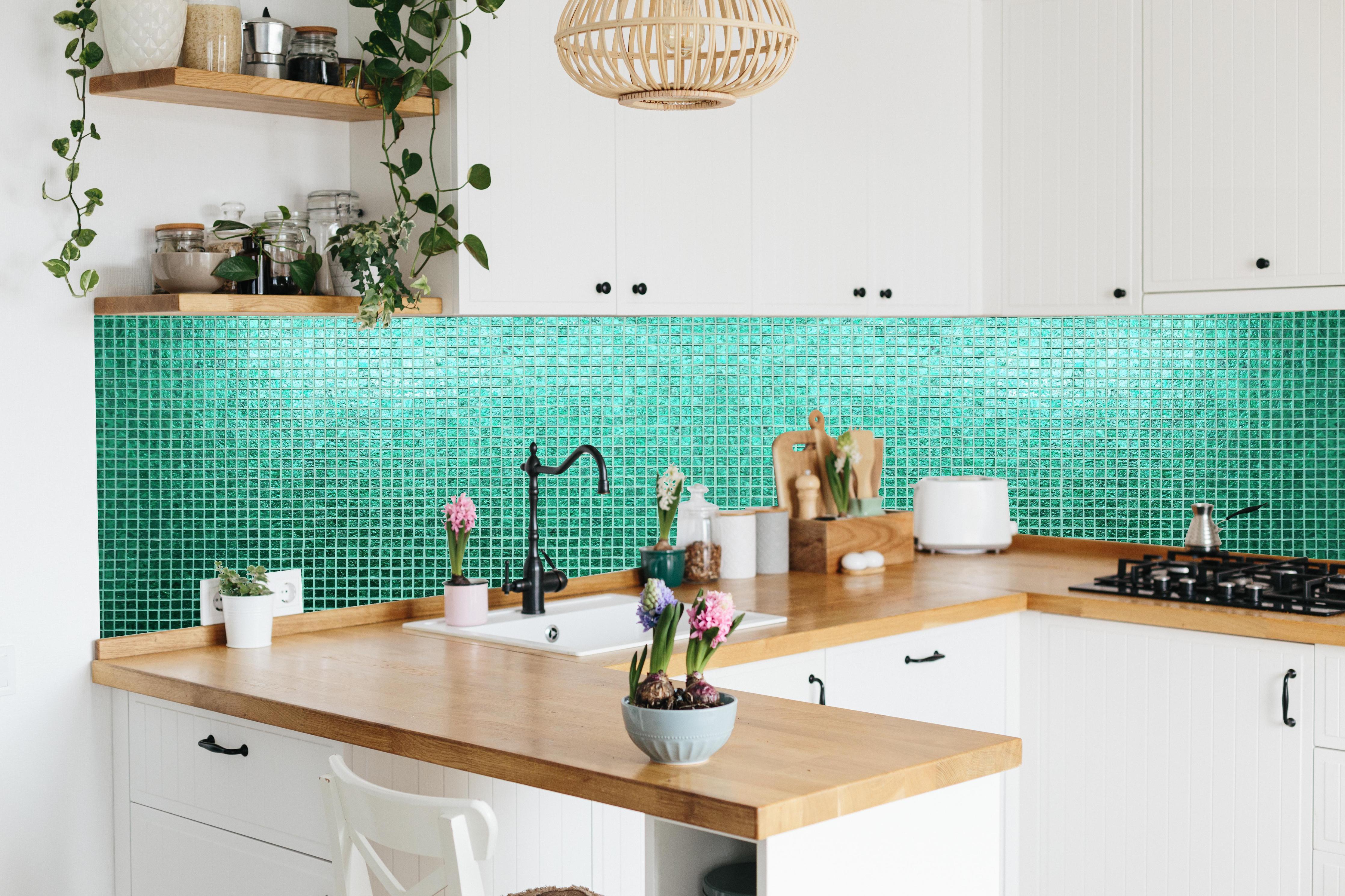 Küche - Strukturierte grüne Fliesenmosaik Textur hinter weißen Hochglanz-Küchenregalen und schwarzem Wasserhahn