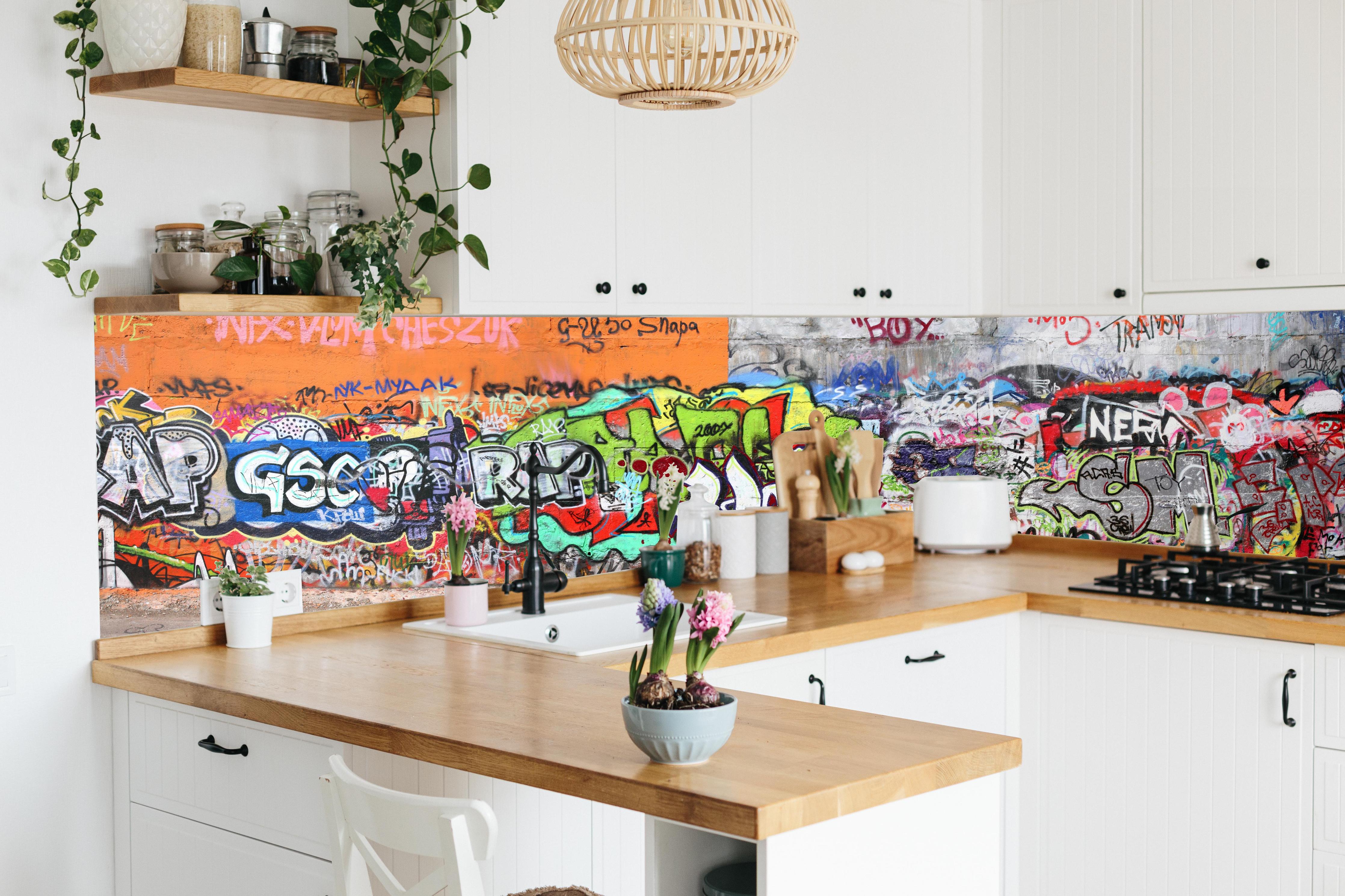 Küche - Textur Urbaner Graffiti-Art Streetstyle hinter weißen Hochglanz-Küchenregalen und schwarzem Wasserhahn