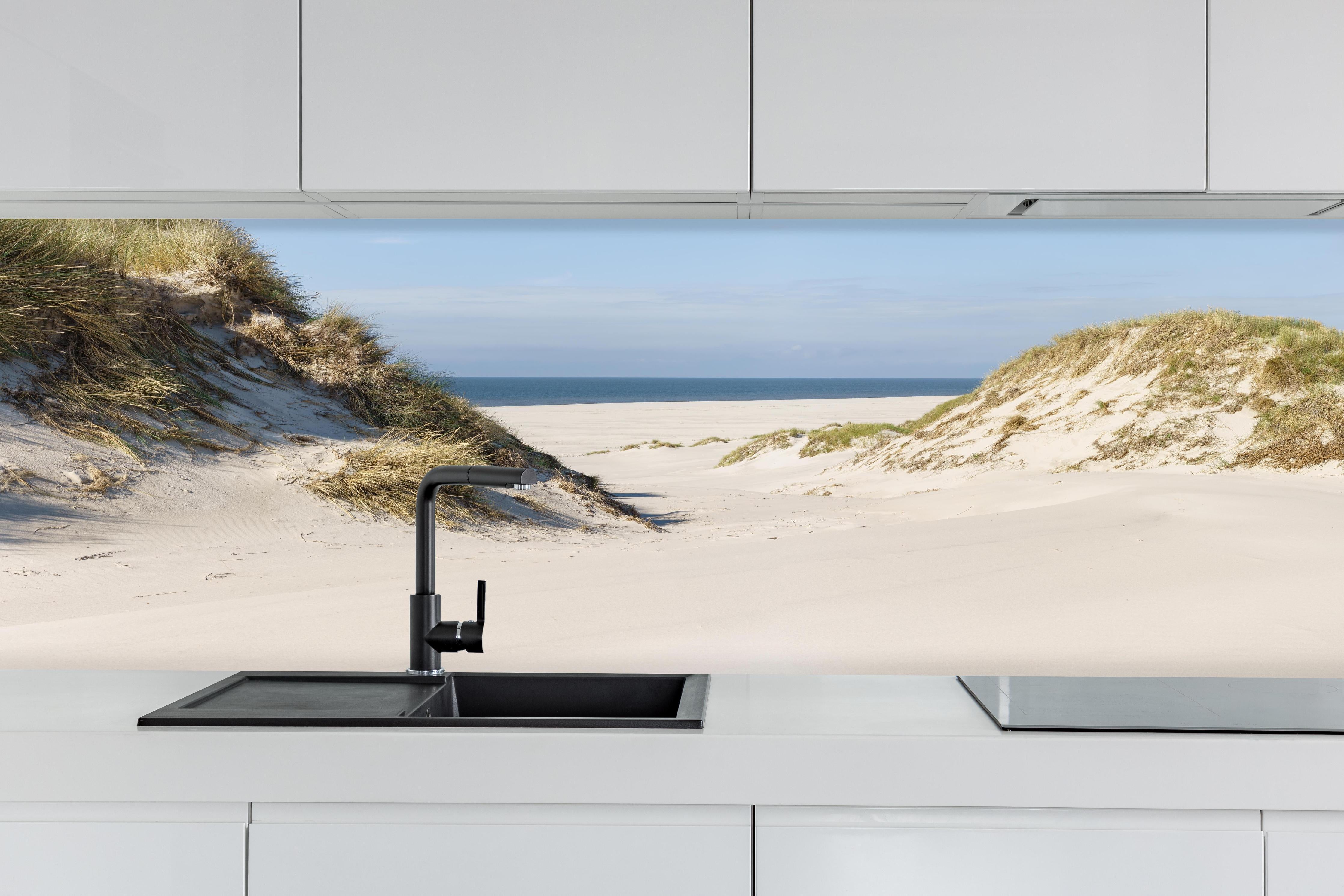 Küche - Traumhafte Sanddüne mit Blick auf das ruhige blaue Meer hinter weißen Hochglanz-Küchenregalen und schwarzem Wasserhahn